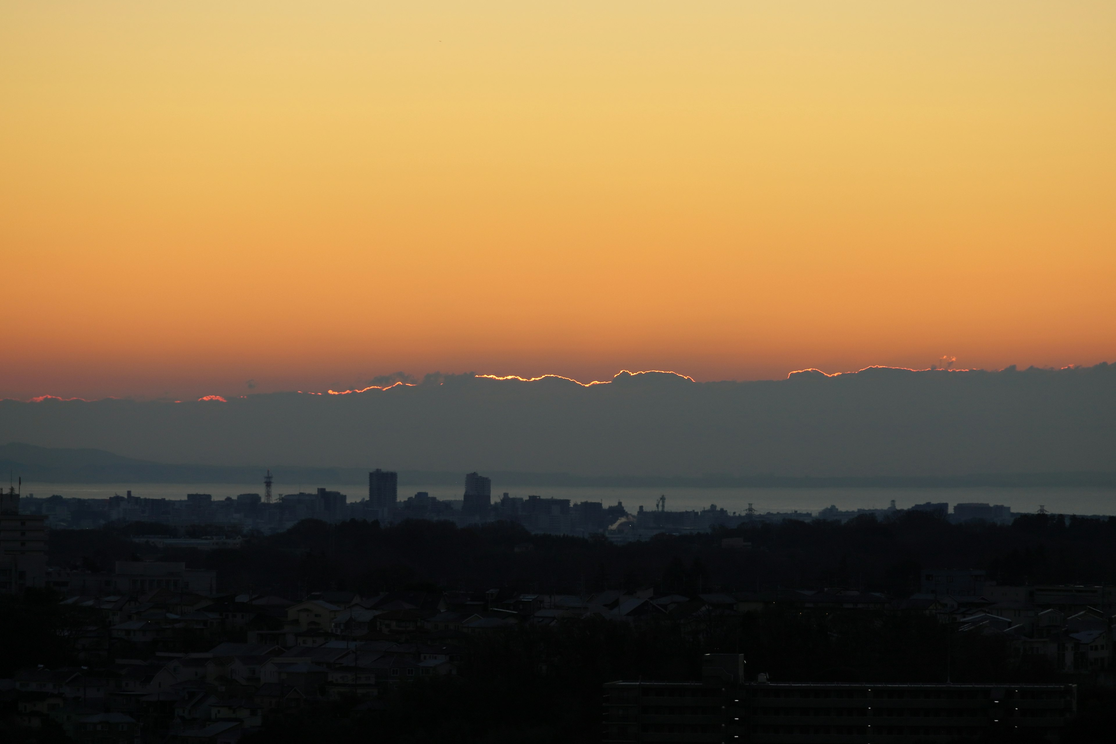 夕焼けの空と山々のシルエットが見える都市の風景