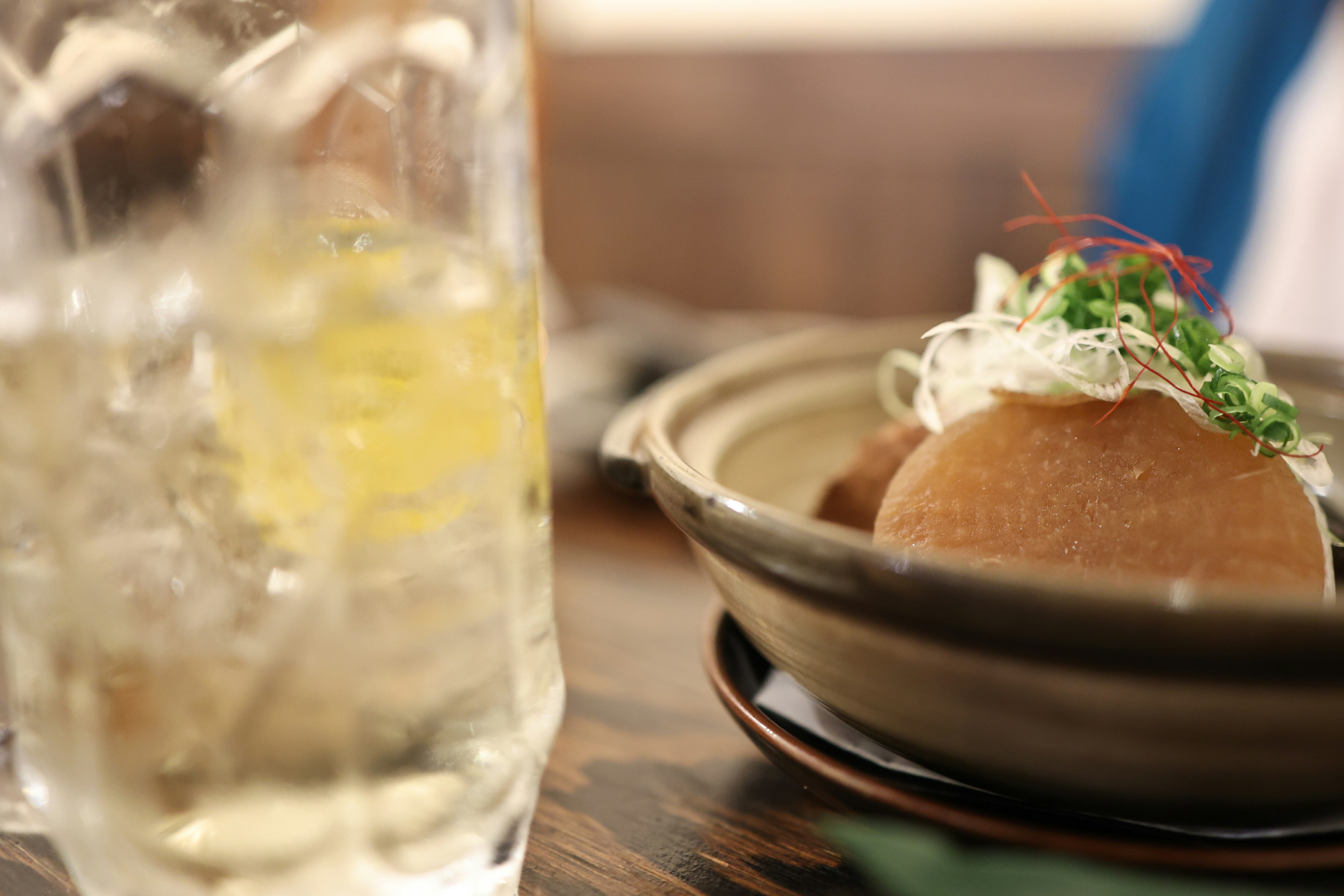 A plate of Japanese food with a drink on a wooden table