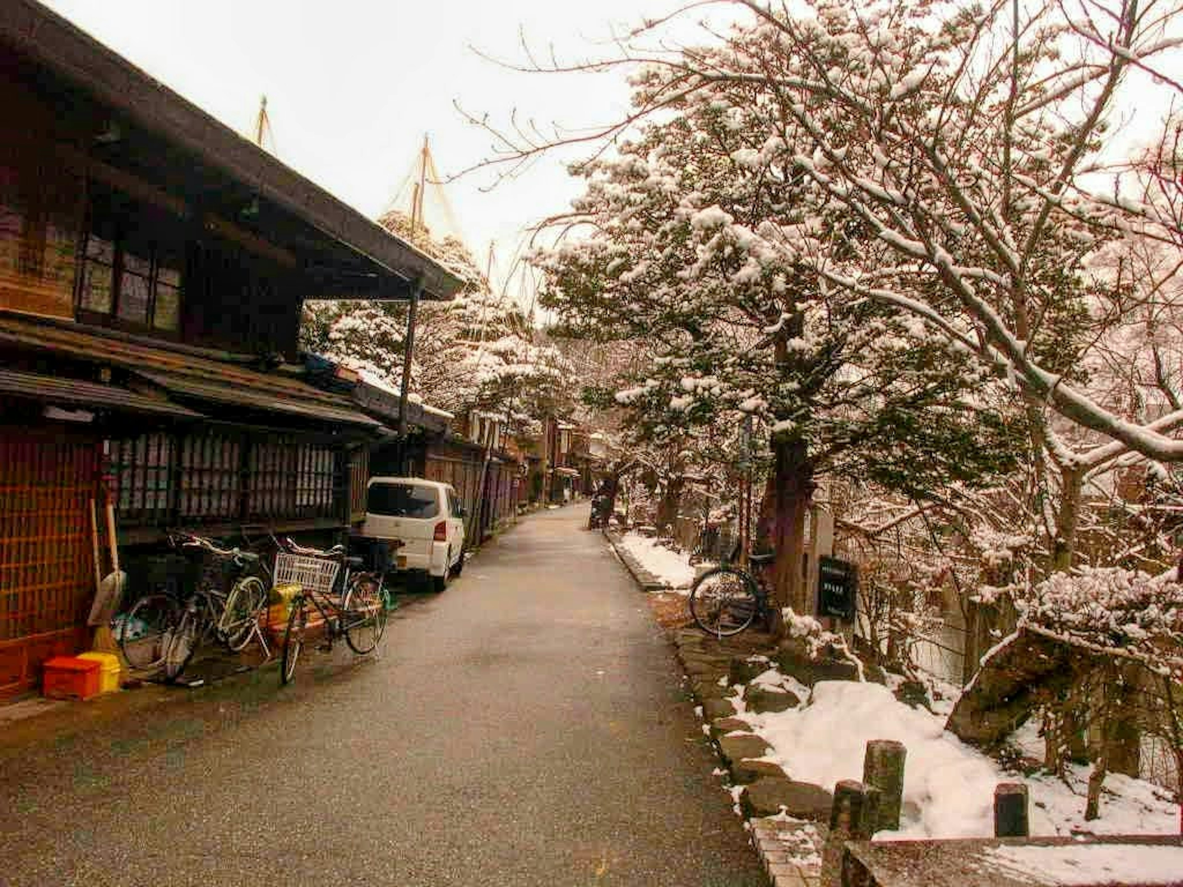 Jalan tenang yang tertutup salju dengan bangunan Jepang tradisional