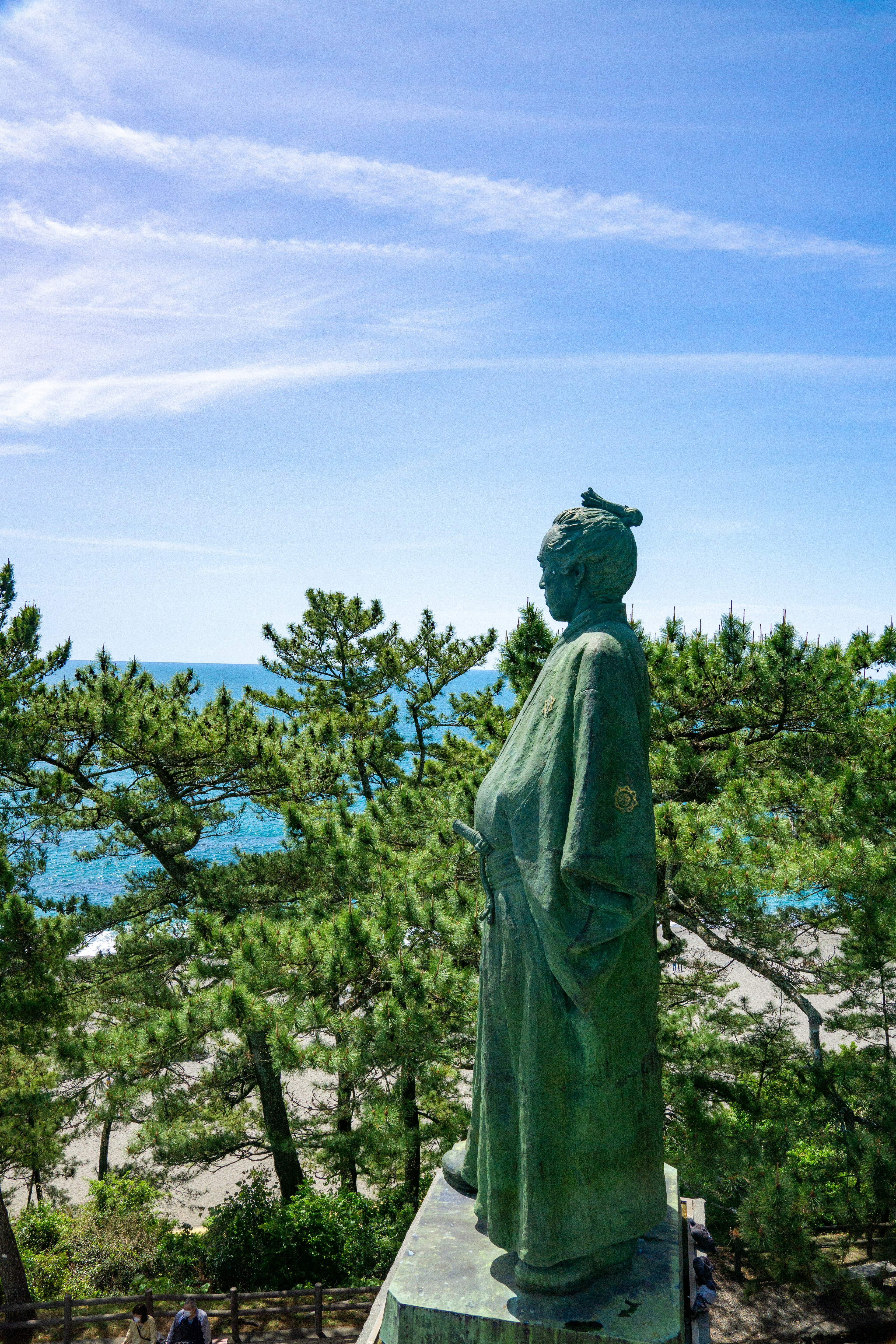 Statue verte surplombant la mer avec des arbres en arrière-plan