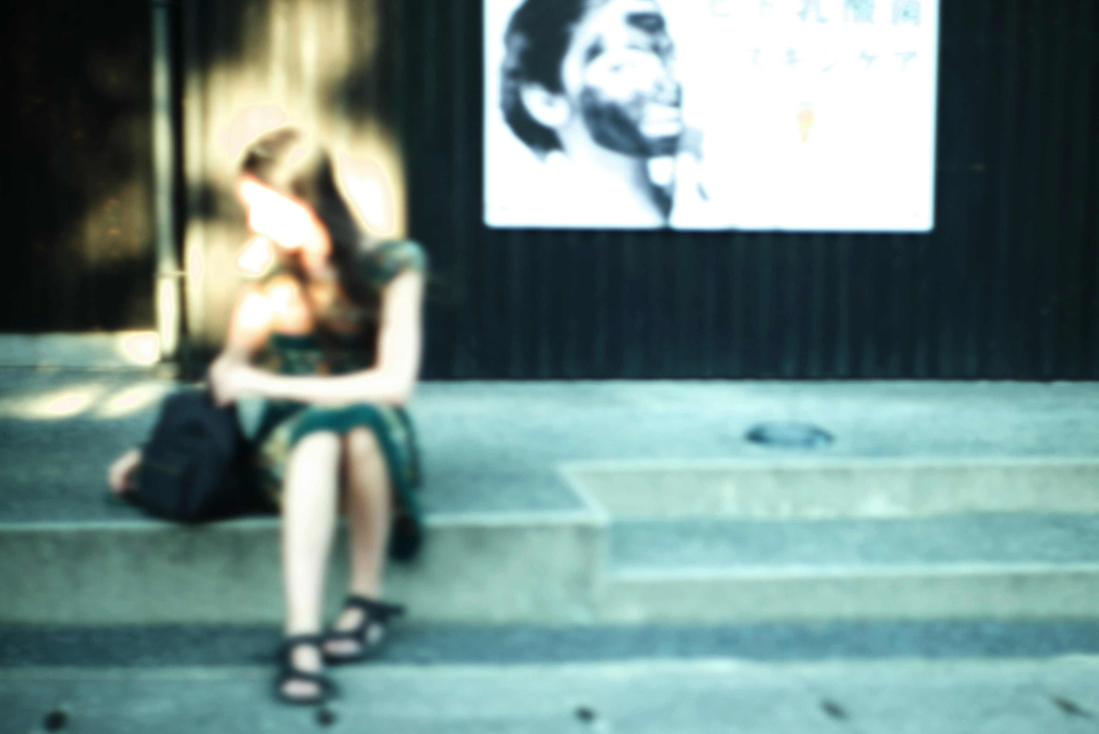 Blurred silhouette of a woman sitting with a poster in the background