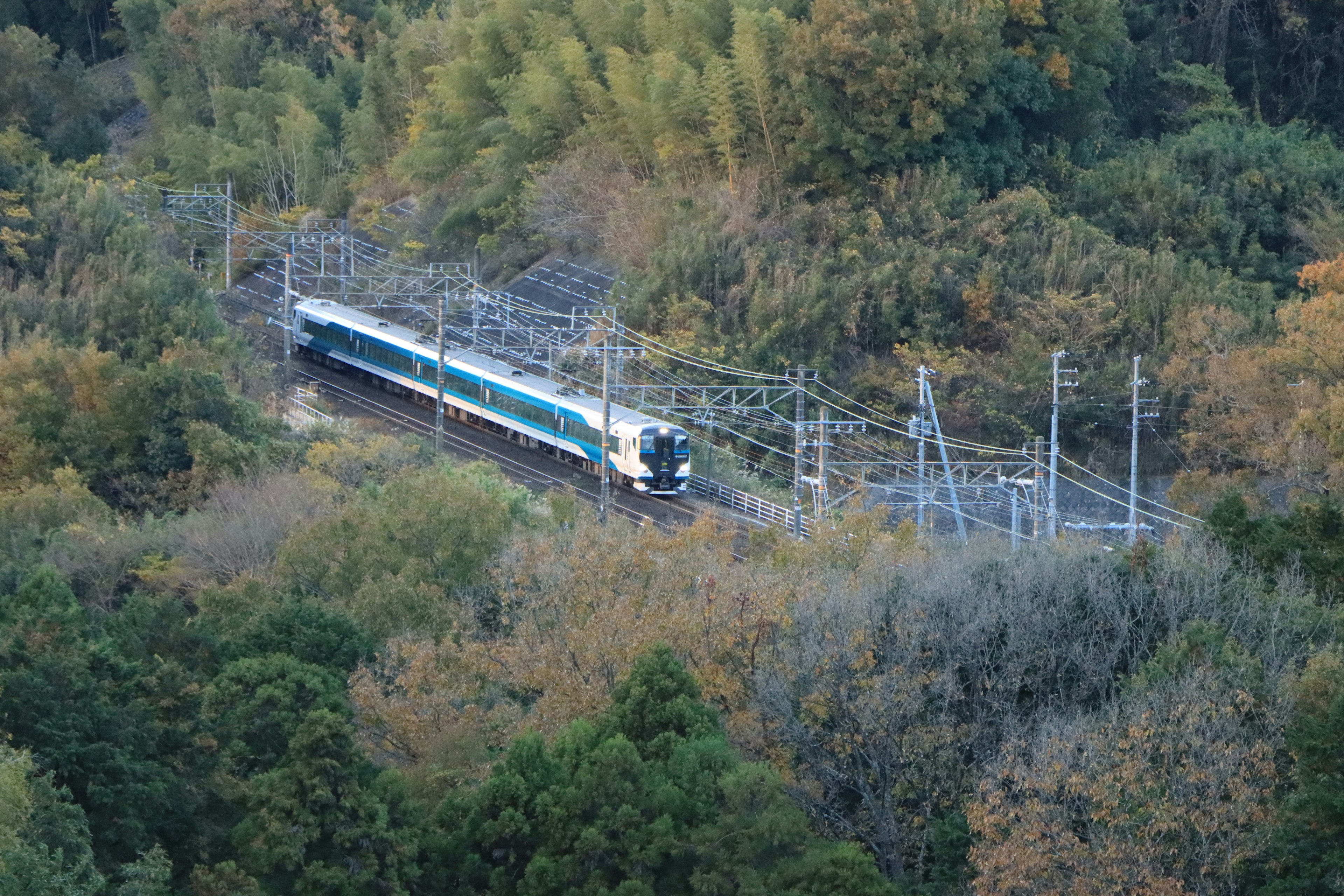 Train traveling through mountainous terrain with autumn foliage