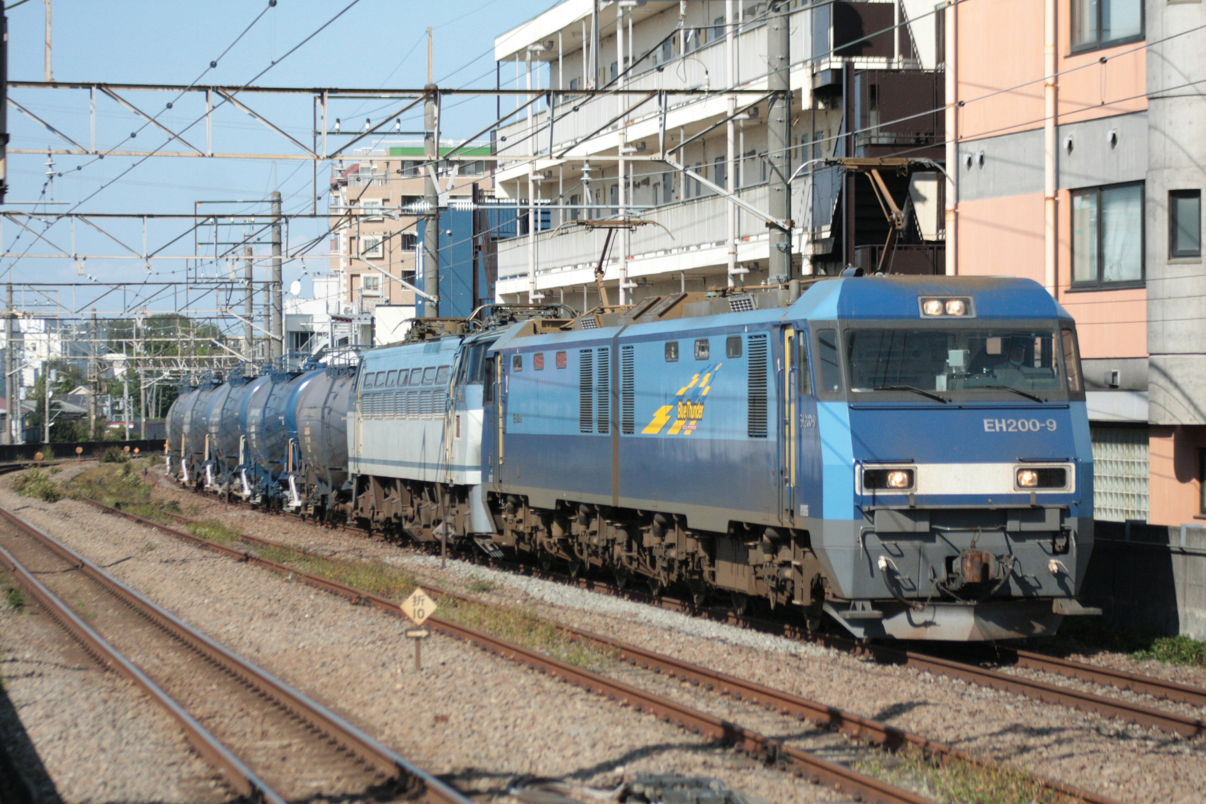 Treno merci blu che corre su binari in un contesto urbano