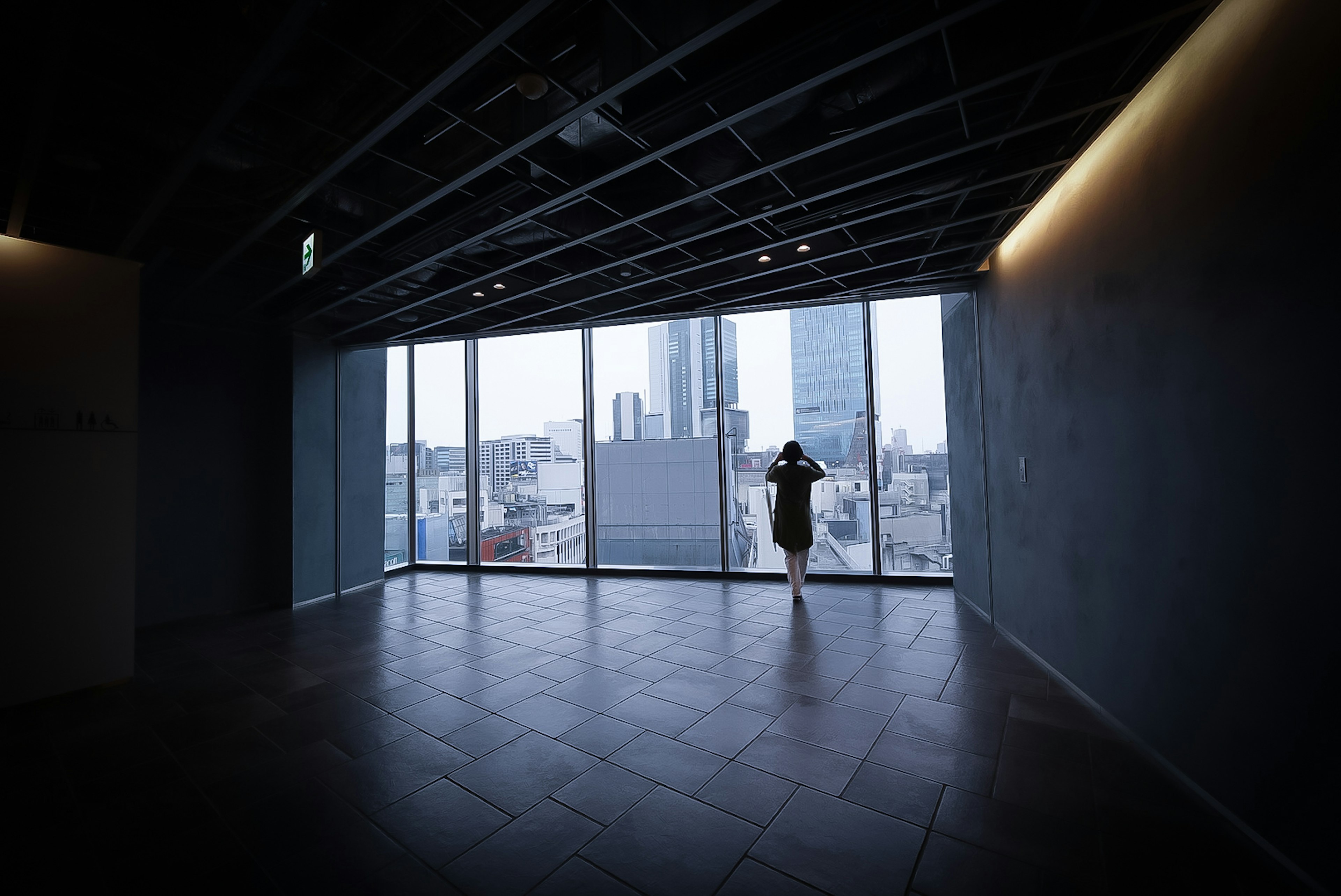 Silueta de una mujer mirando por la ventana de un edificio de oficinas moderno