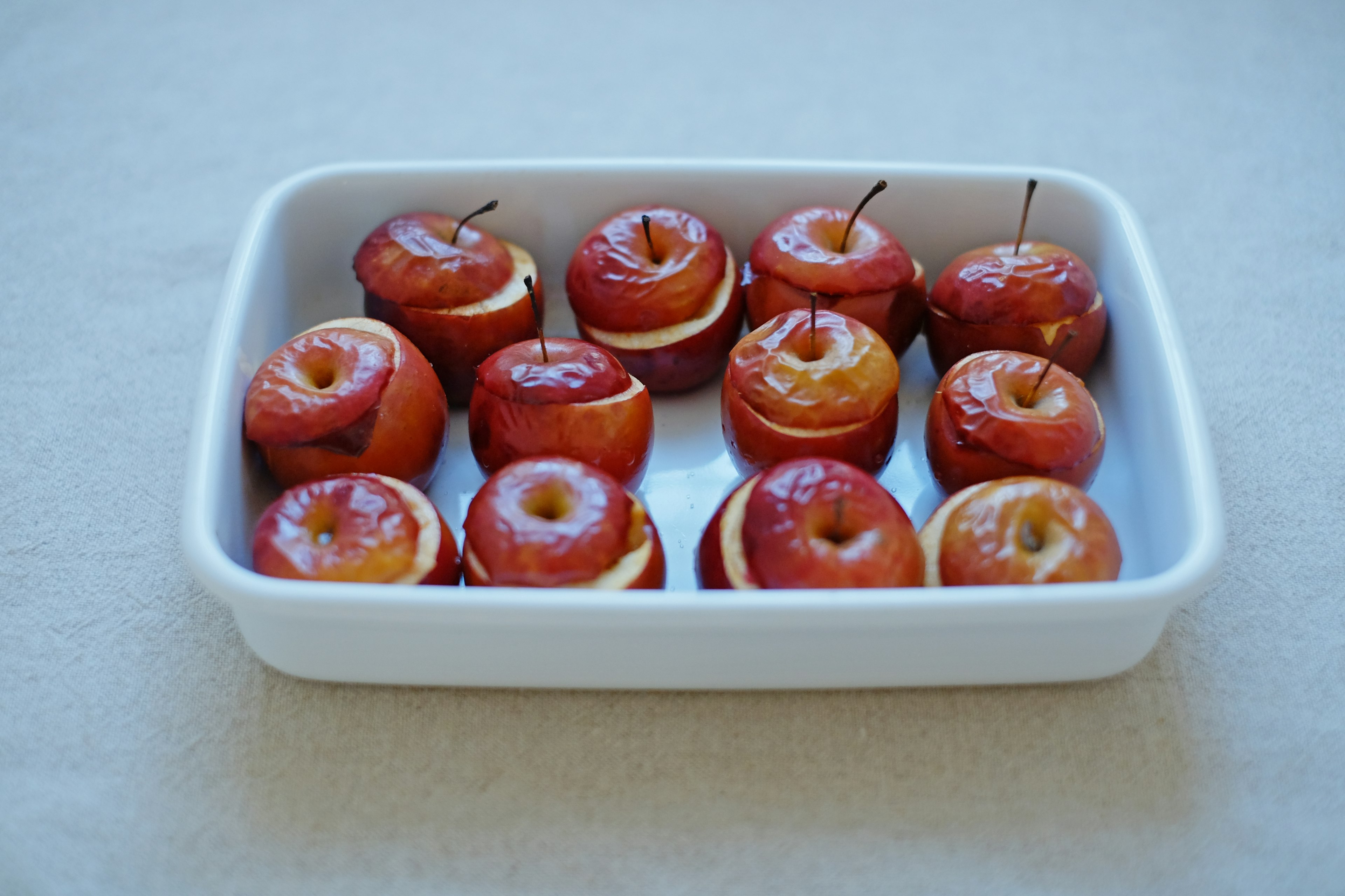 Un plat blanc rempli de pommes rouges cuites