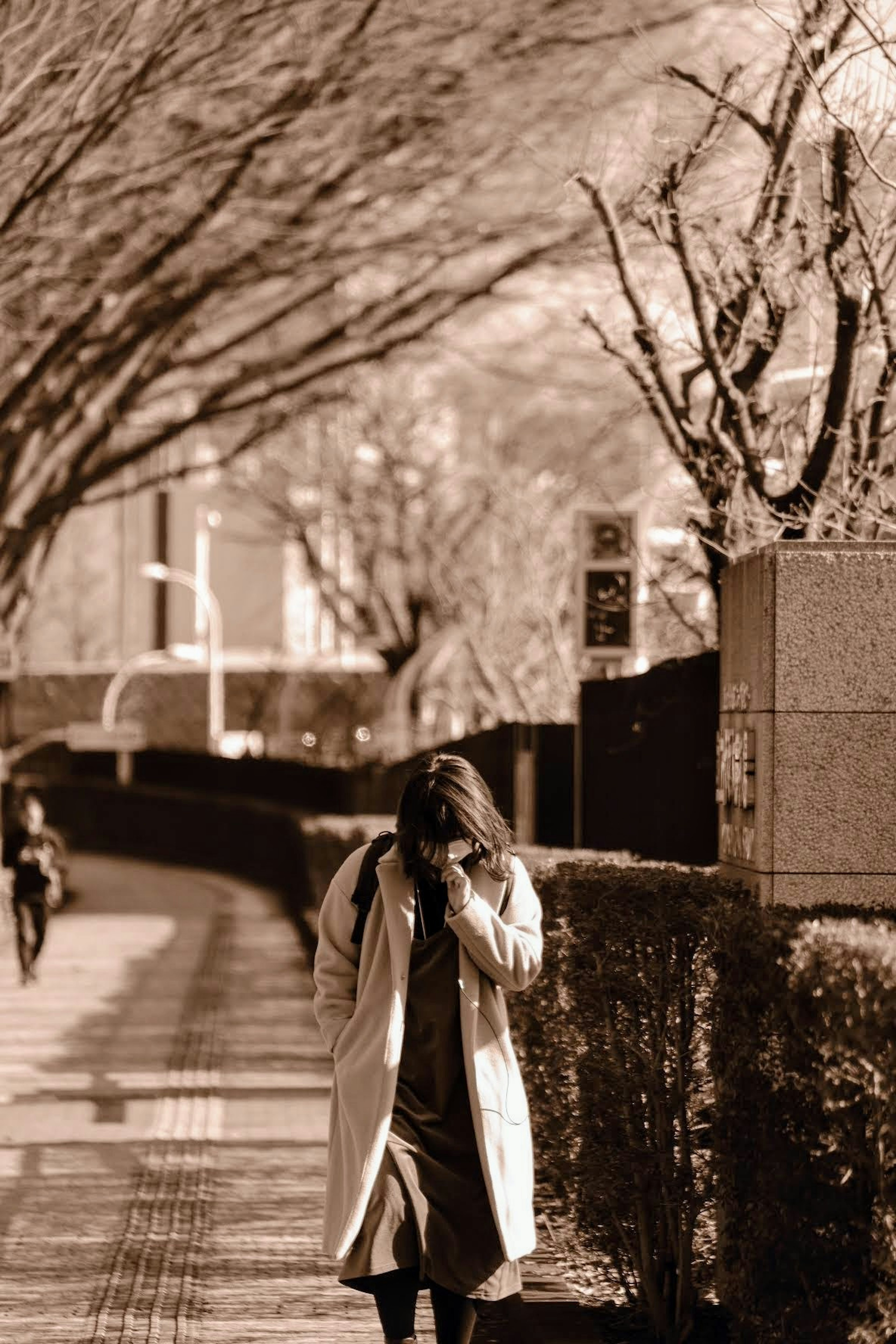 A woman in a white coat walking along a city street