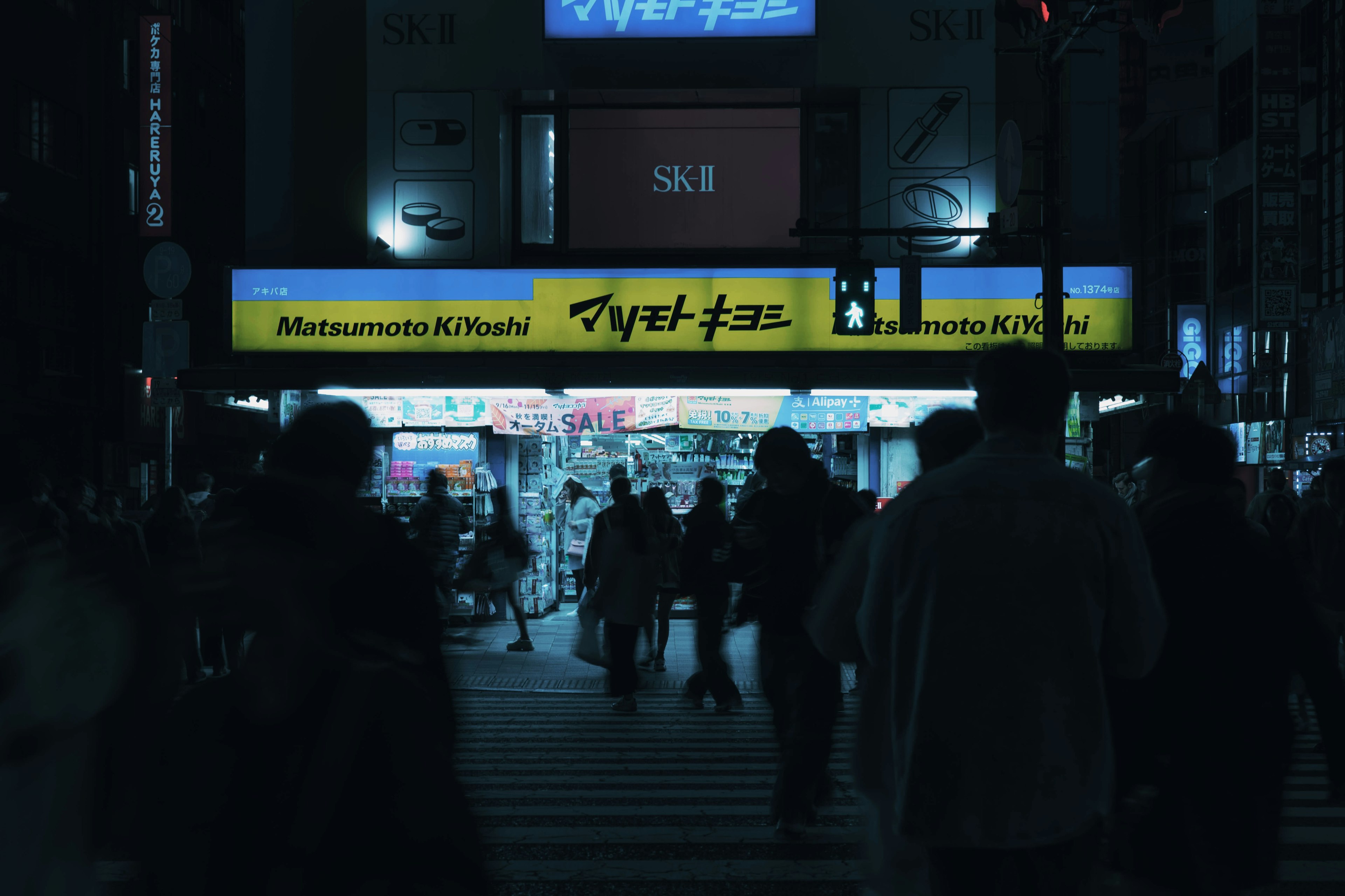 People walking in a busy street at night bright signage is prominent