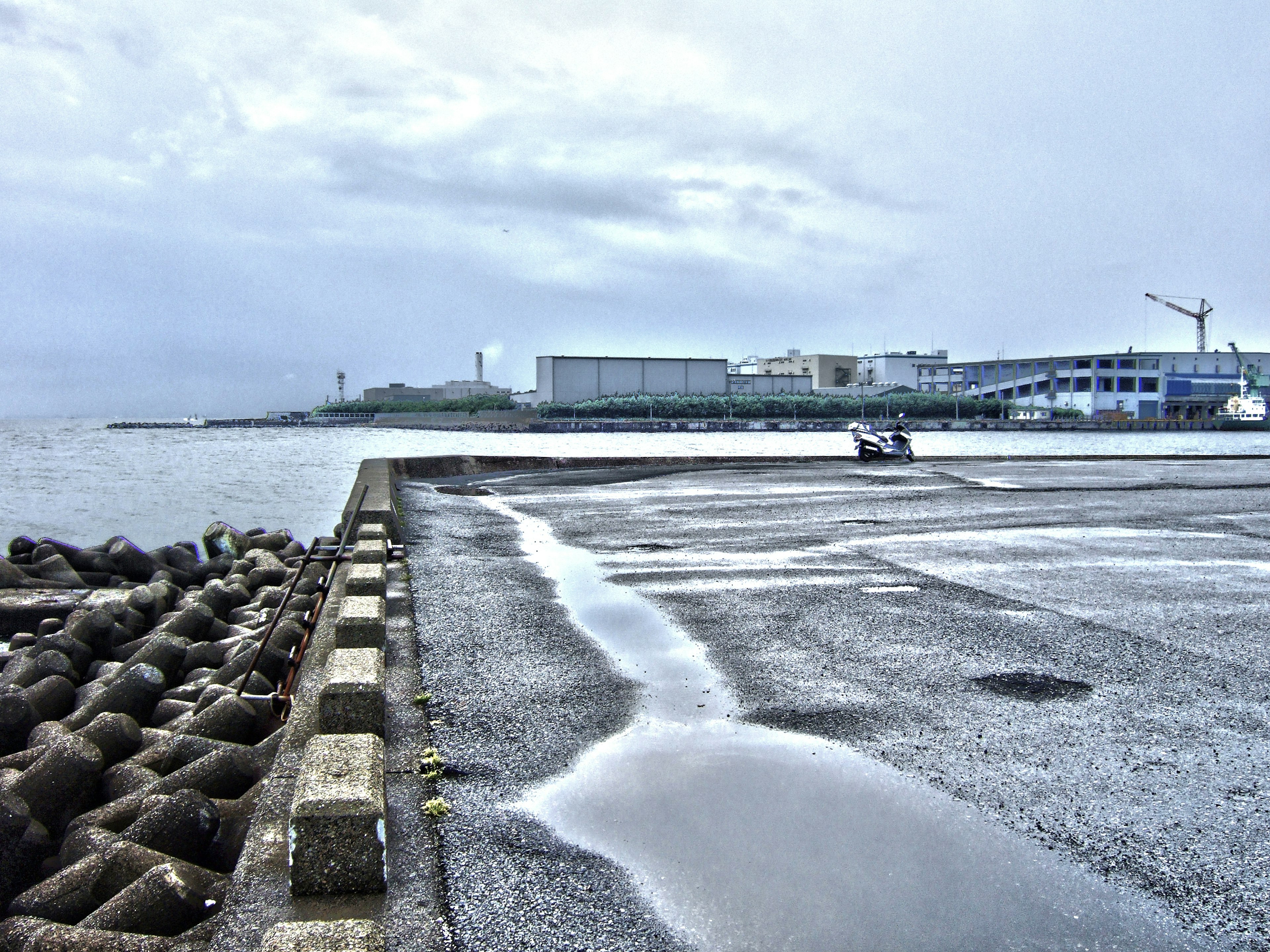 Harbor scene after rain with puddles on concrete pier and nearby buildings