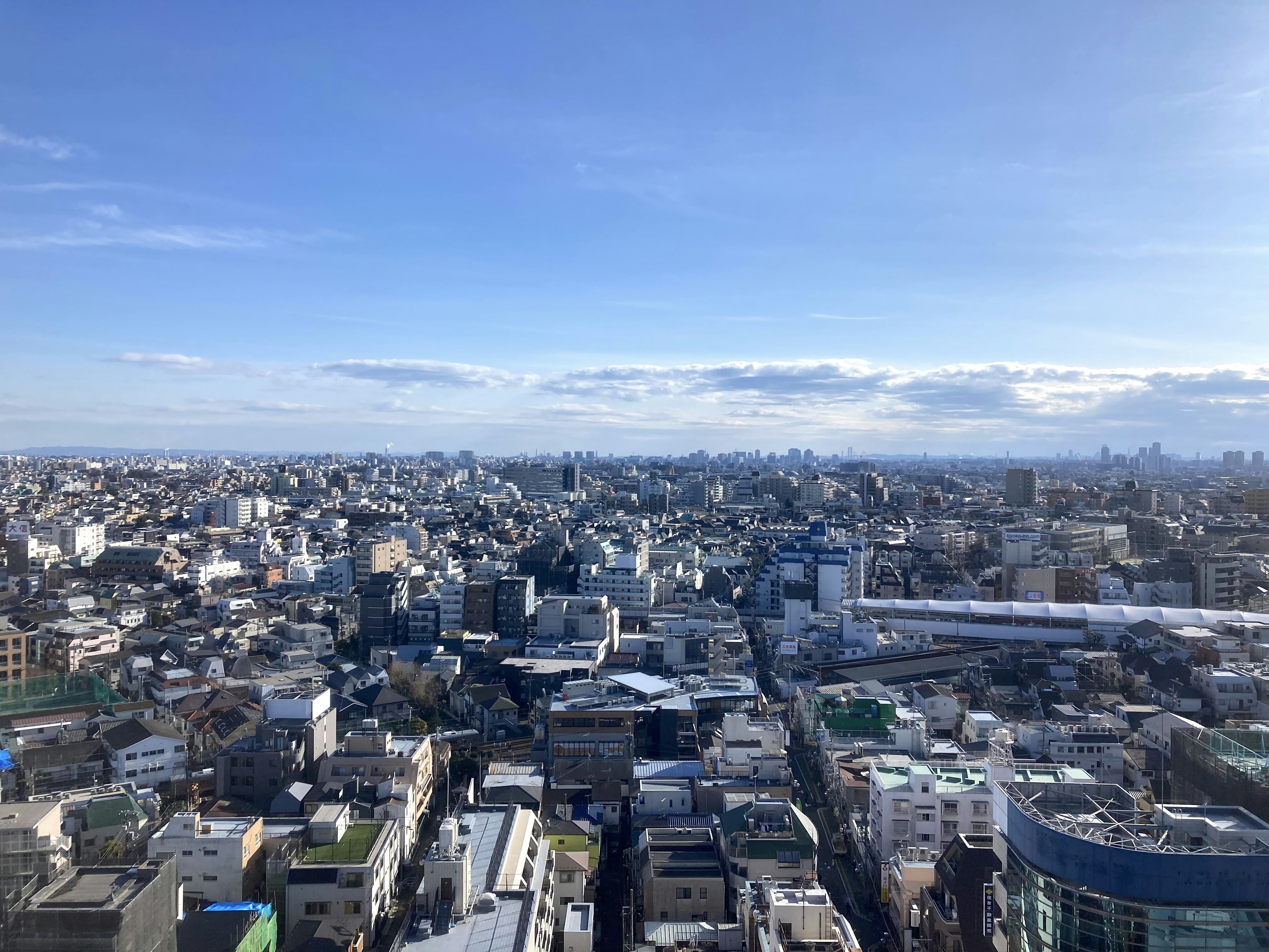 Vista panorámica del vasto paisaje urbano de Tokio con cielo azul y nubes dispersas