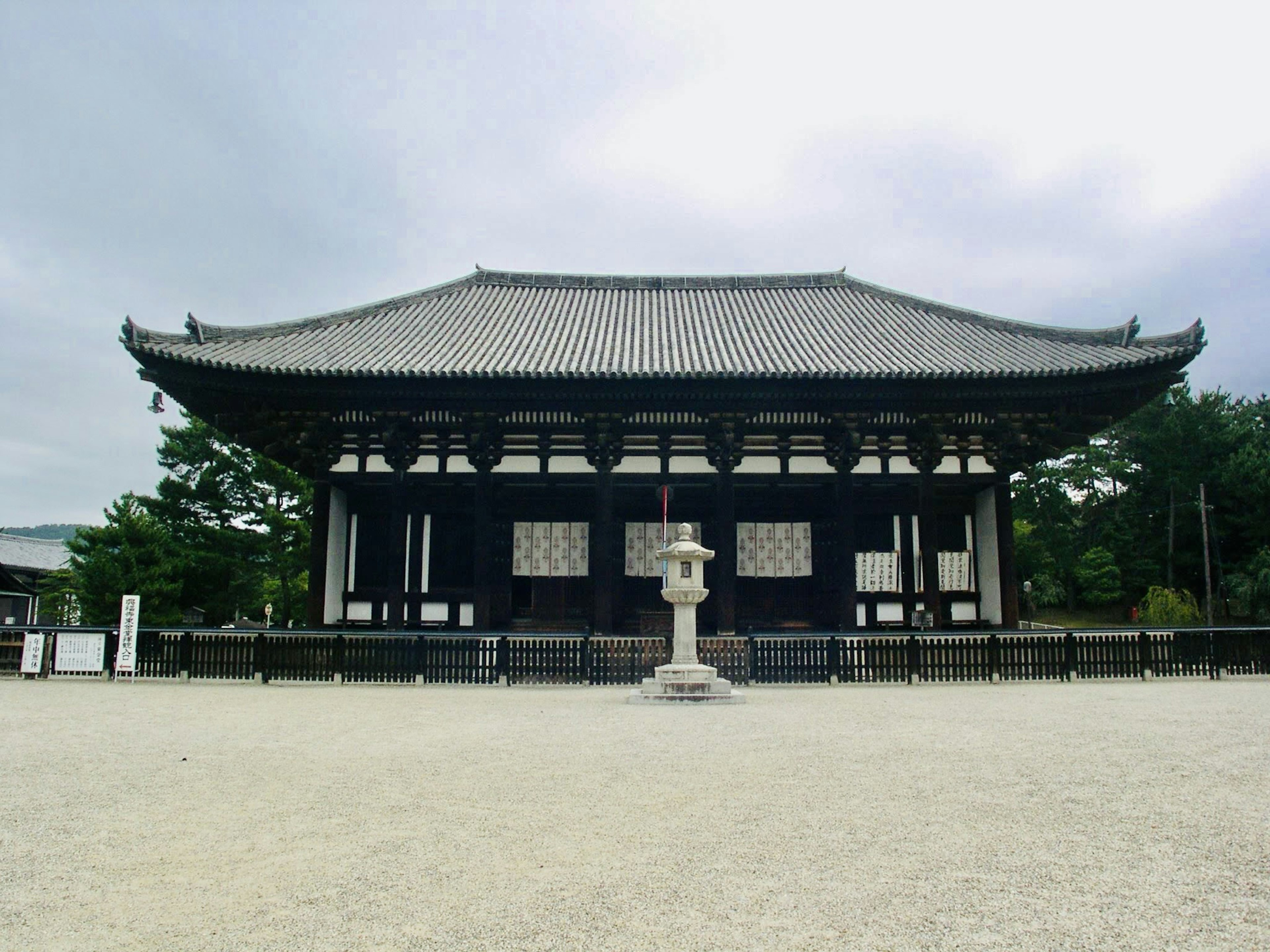 黒と白の伝統的な日本建築の寺院が広場に立っている