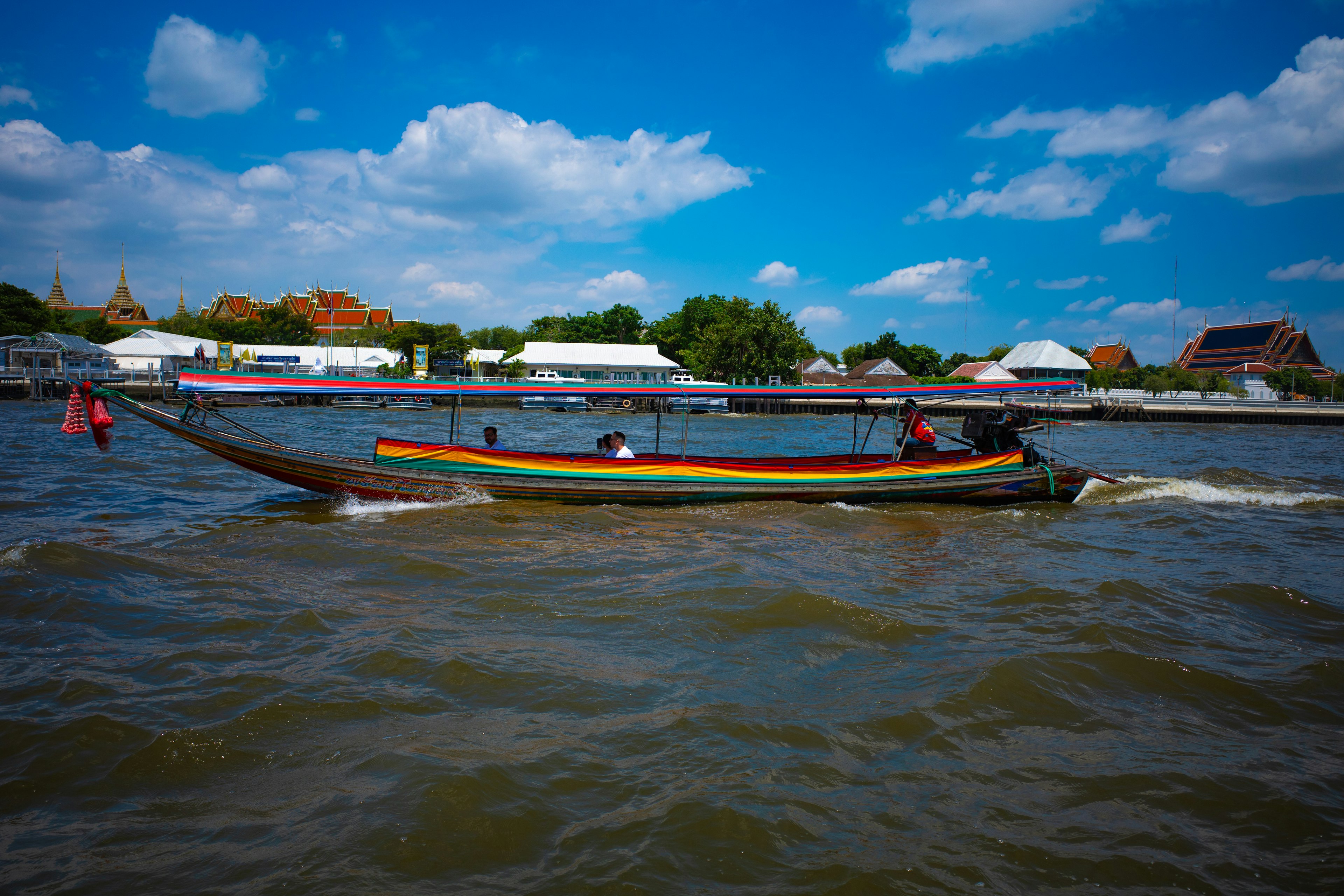 Perahu berwarna-warni berlayar di sungai di bawah langit biru