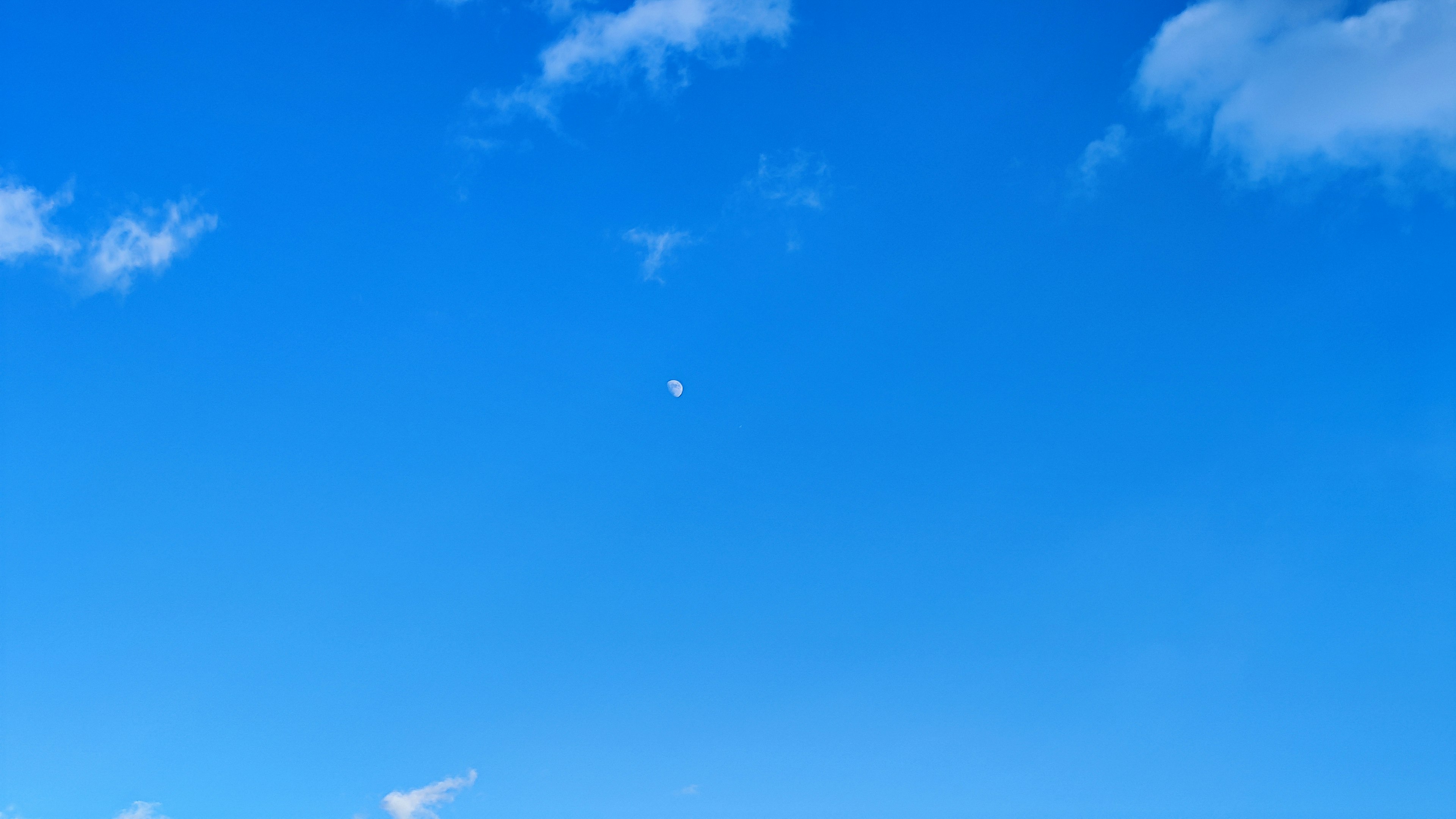 青い空に浮かぶ白い雲と小さな月