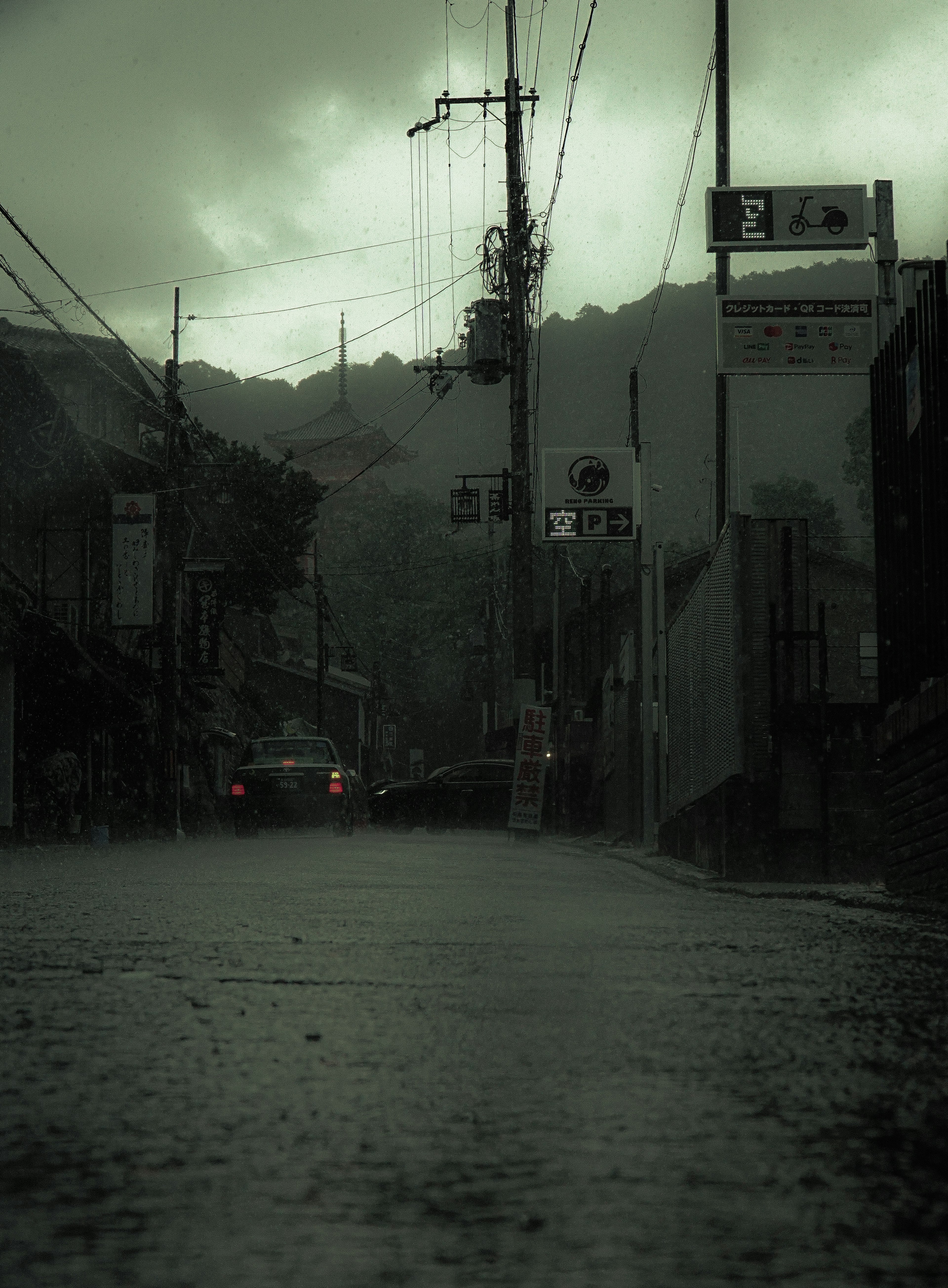 Rain-soaked street scene with dark sky and reflections on wet pavement