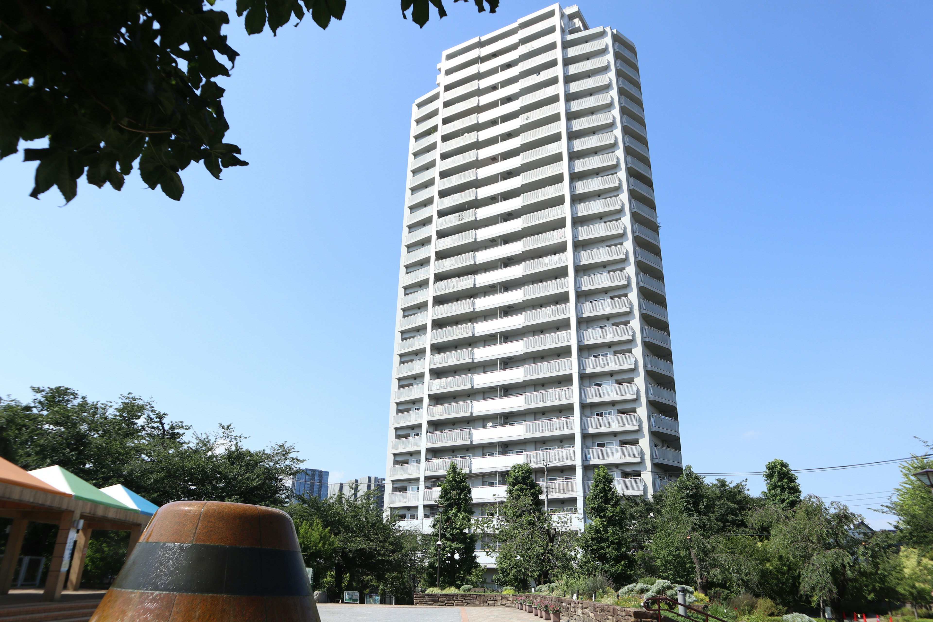 Alto edificio residenziale con cielo blu chiaro e vegetazione in primo piano