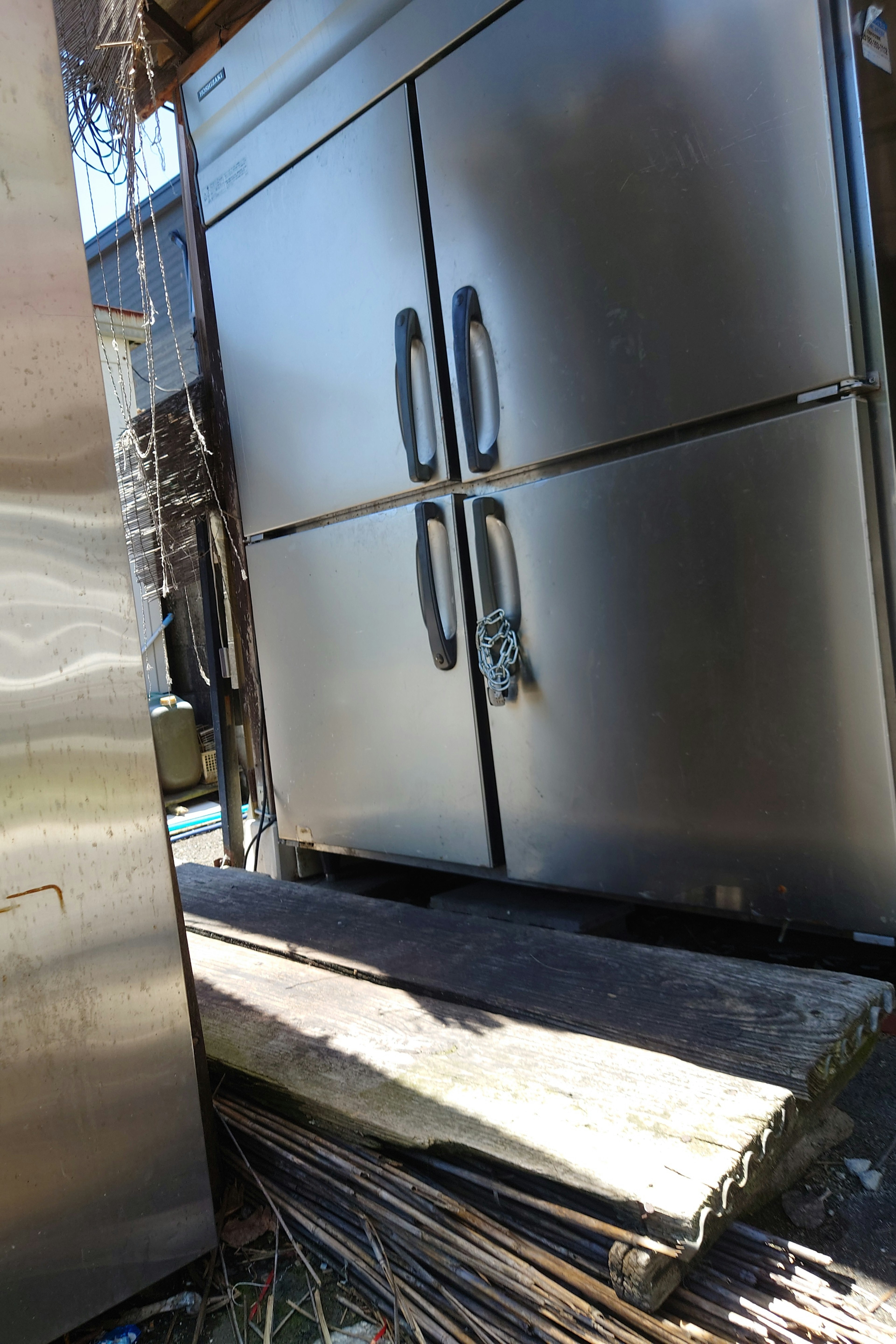 Exterior de un refrigerador de metal con tablones de madera cerca