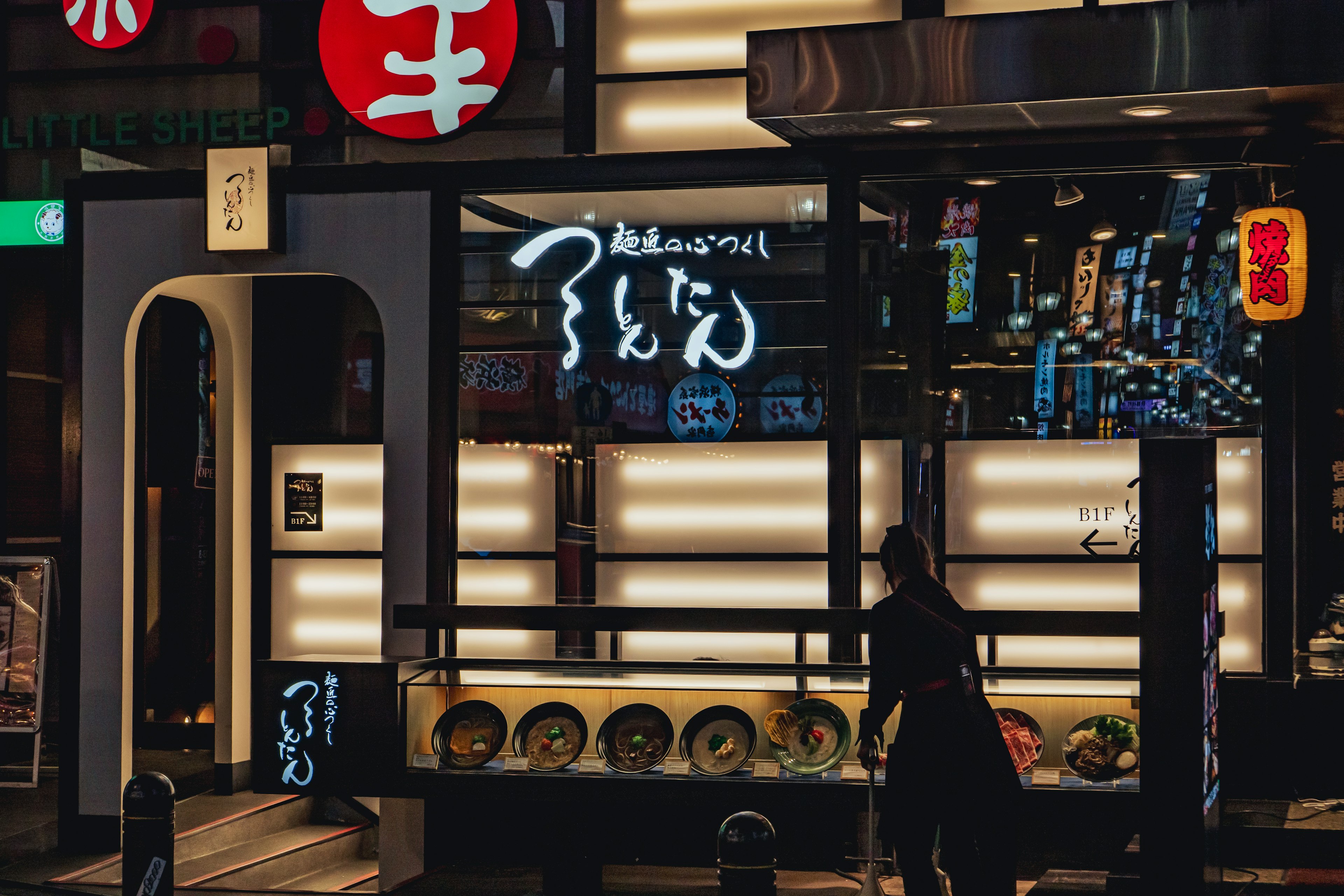 Night view of a Japanese ramen shop with bright signage and displayed dishes