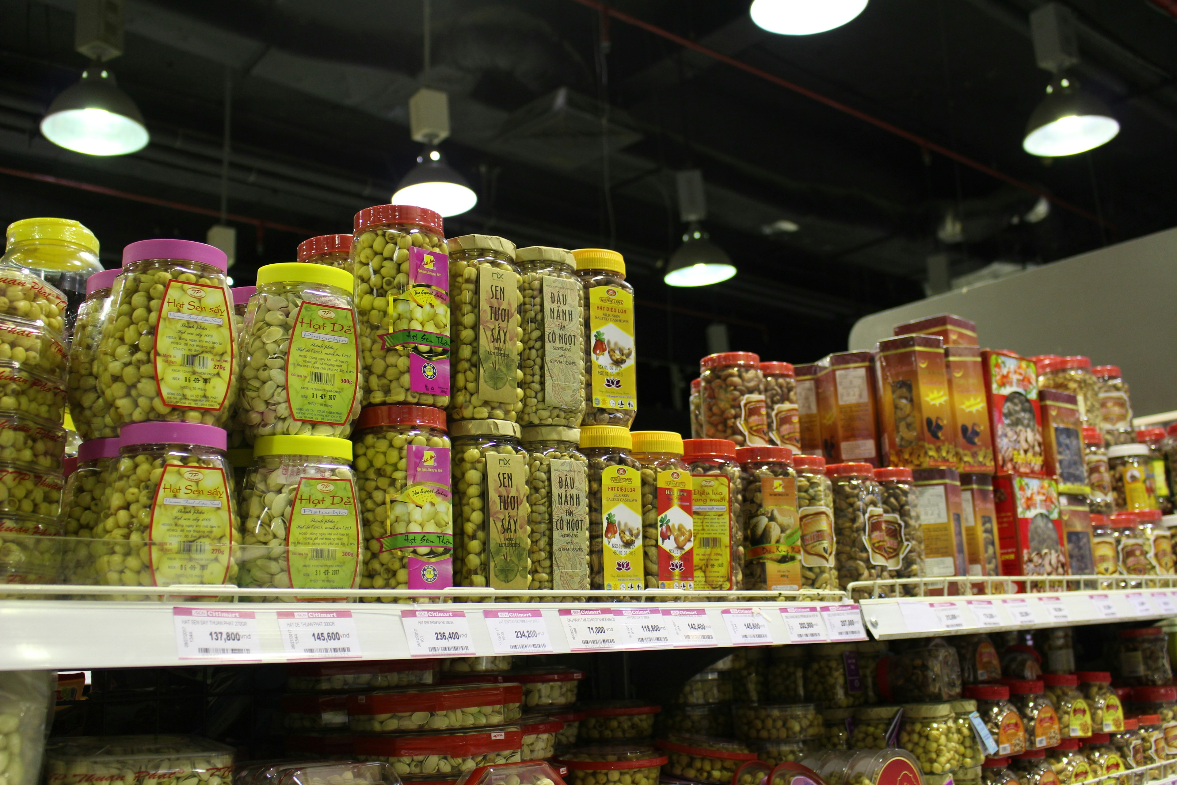 Various jars of olives lined up on a supermarket shelf