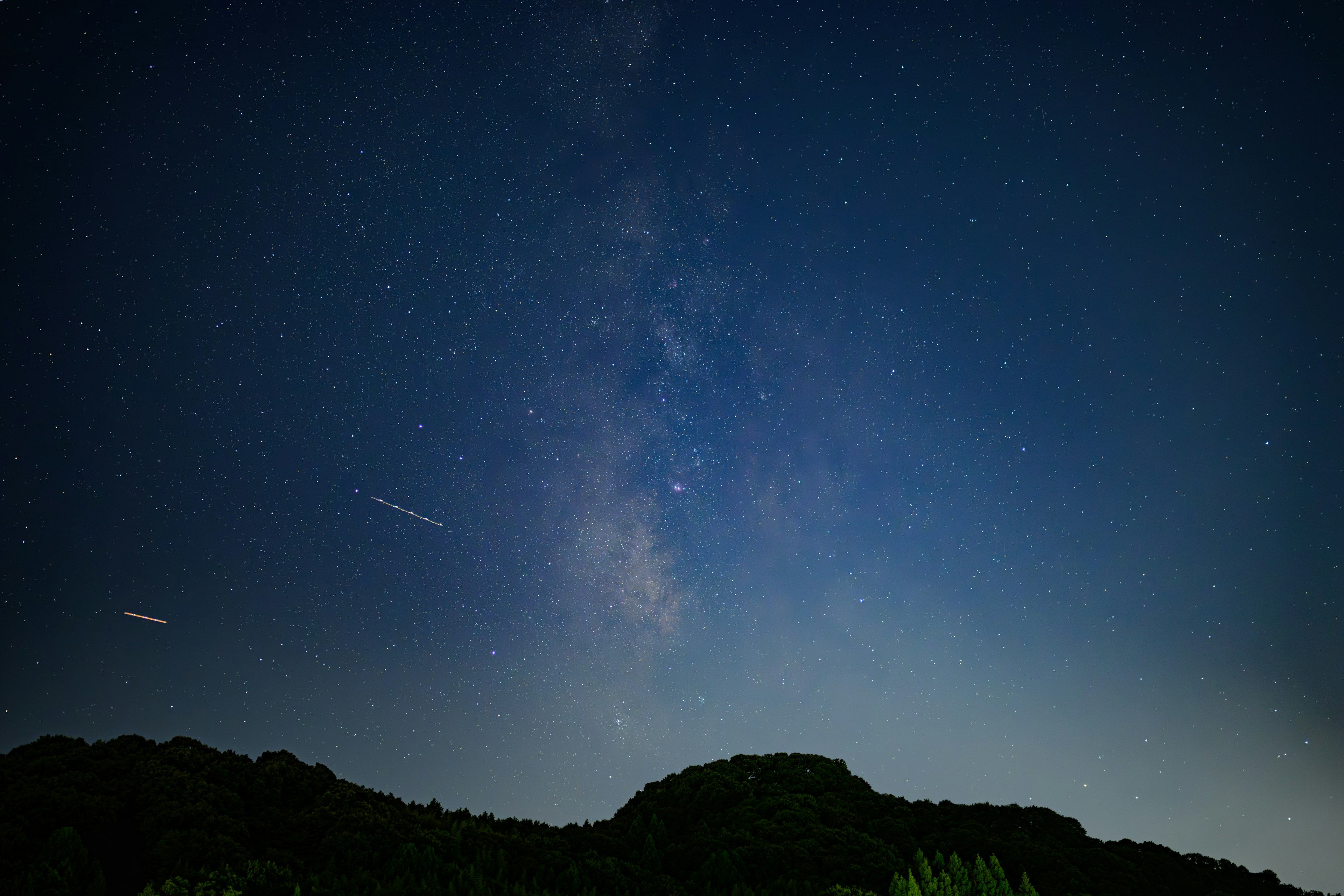 Milky Way stretching across the night sky with mountain silhouette