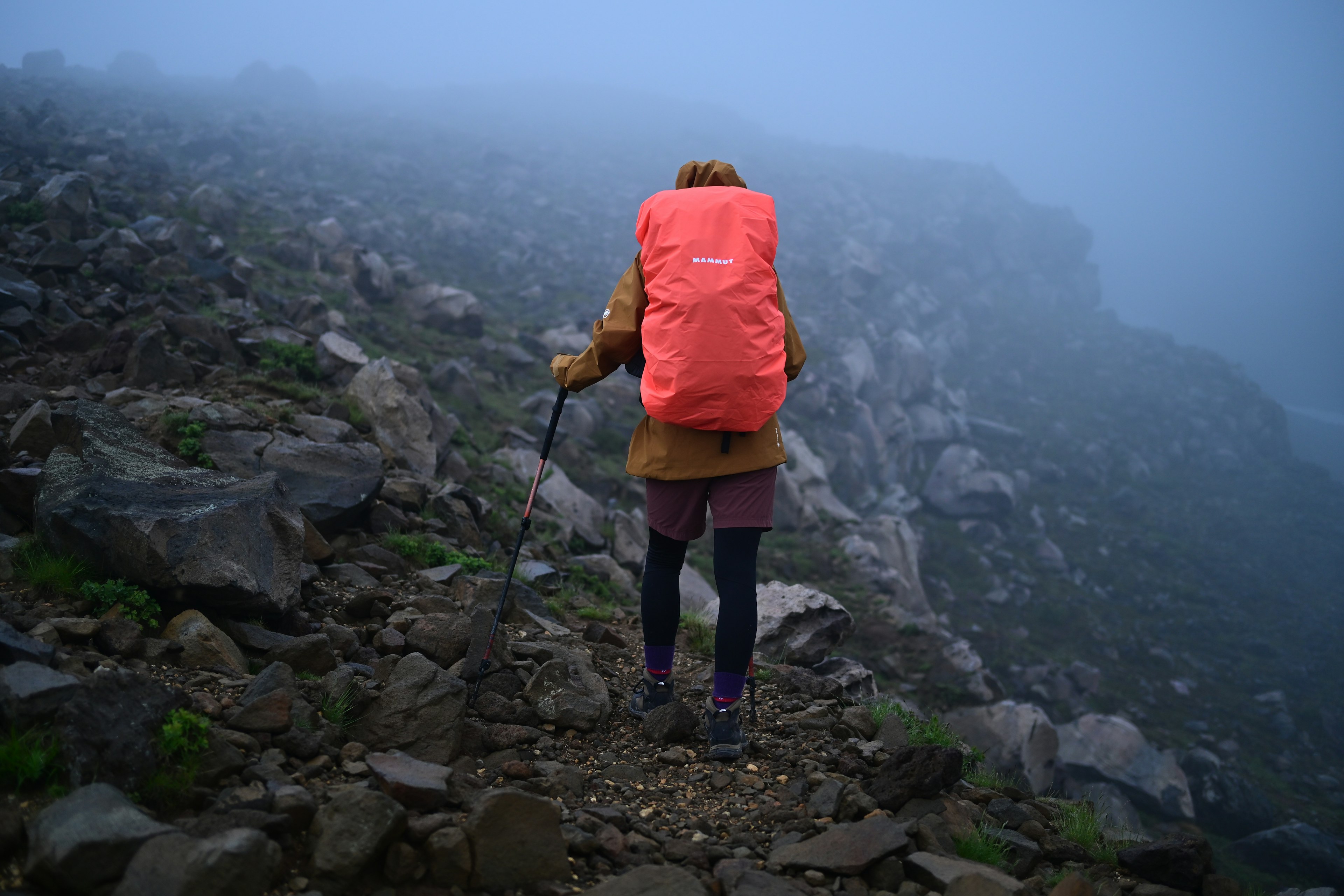 Wanderer im Nebel mit einem orangefarbenen Rucksack