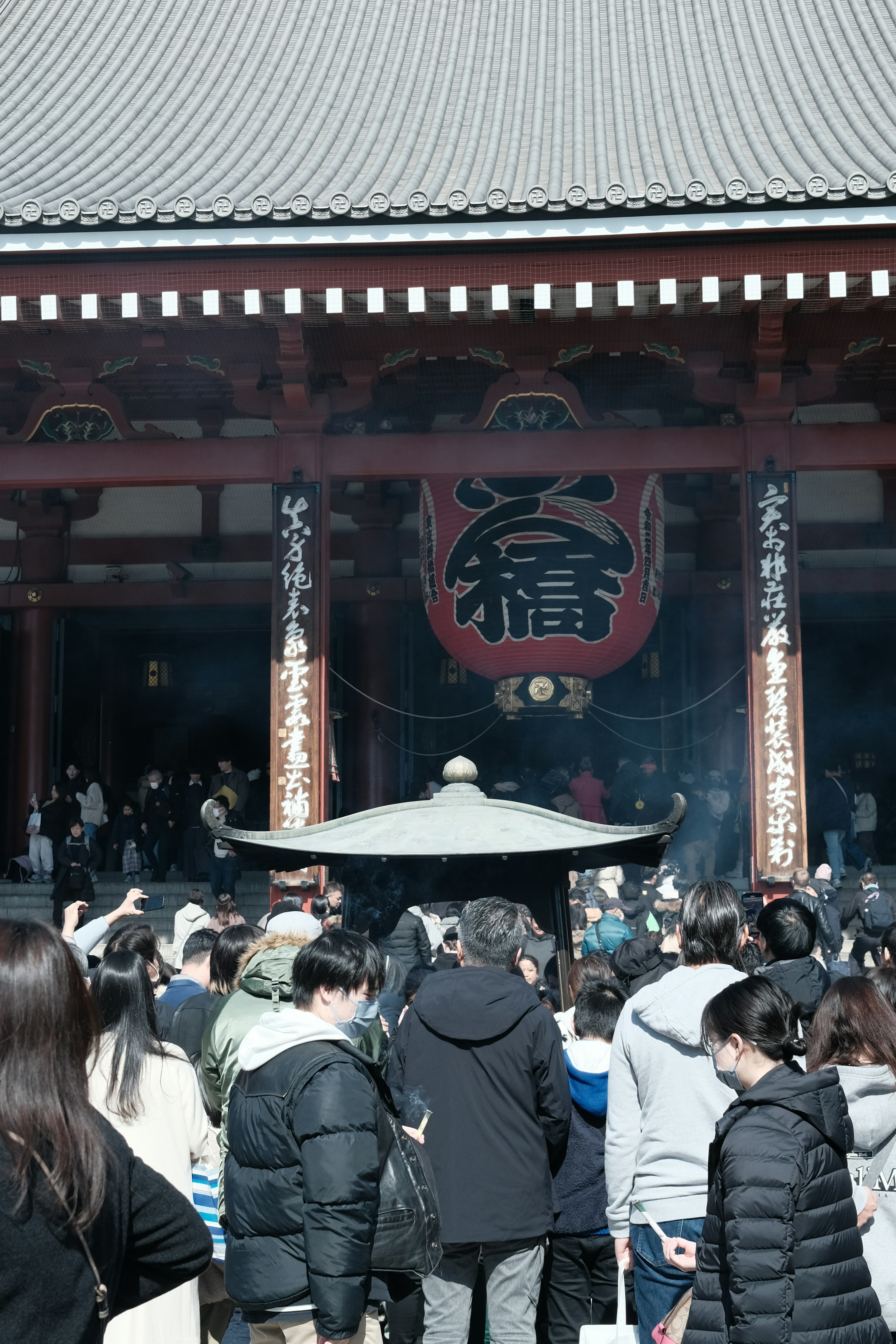 Tourists gathered in front of Senso-ji Temple with smoke rising from the incense burner