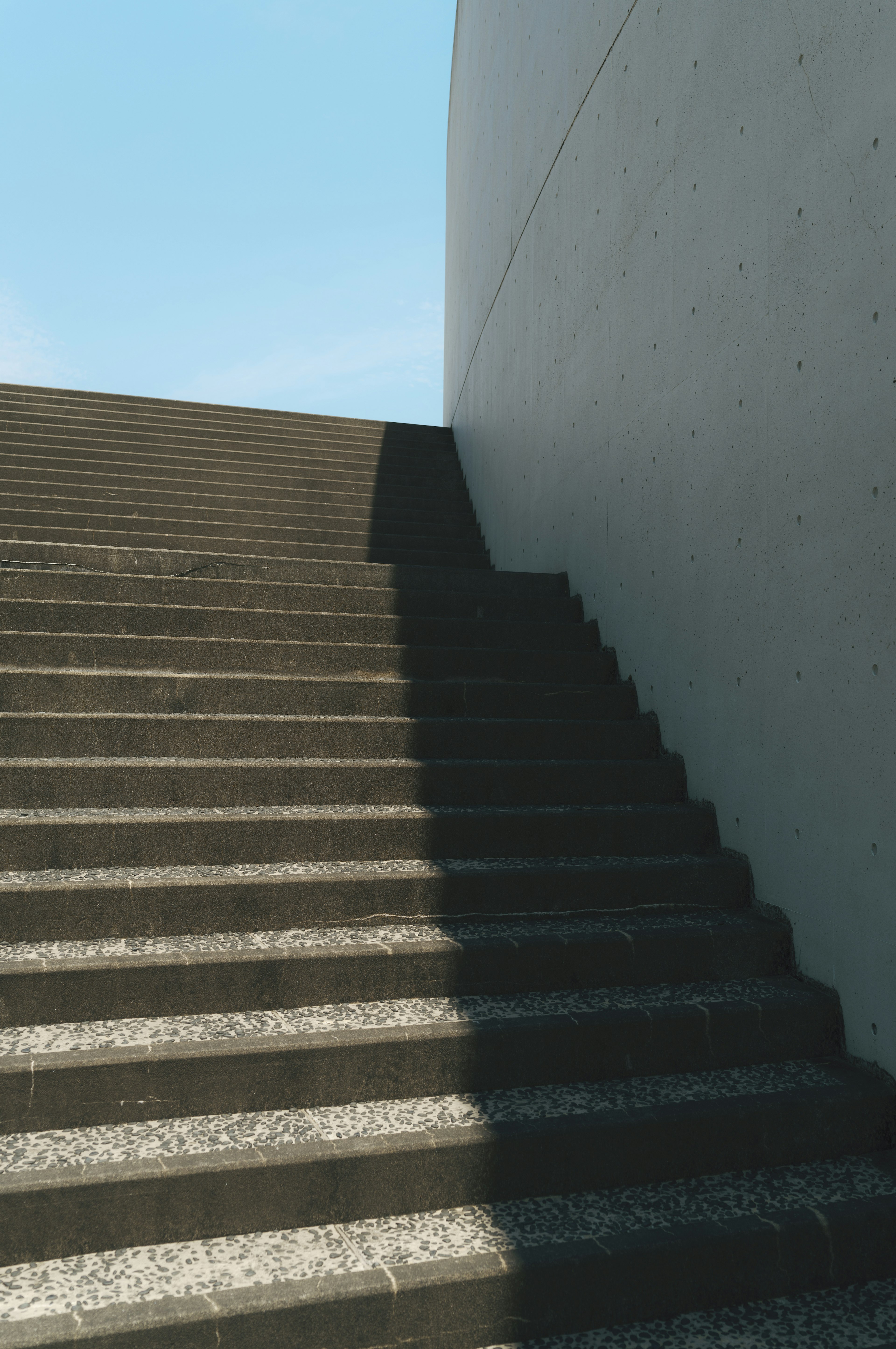 Diseño arquitectónico moderno que destaca el contraste de sombras y cielo brillante en las escaleras