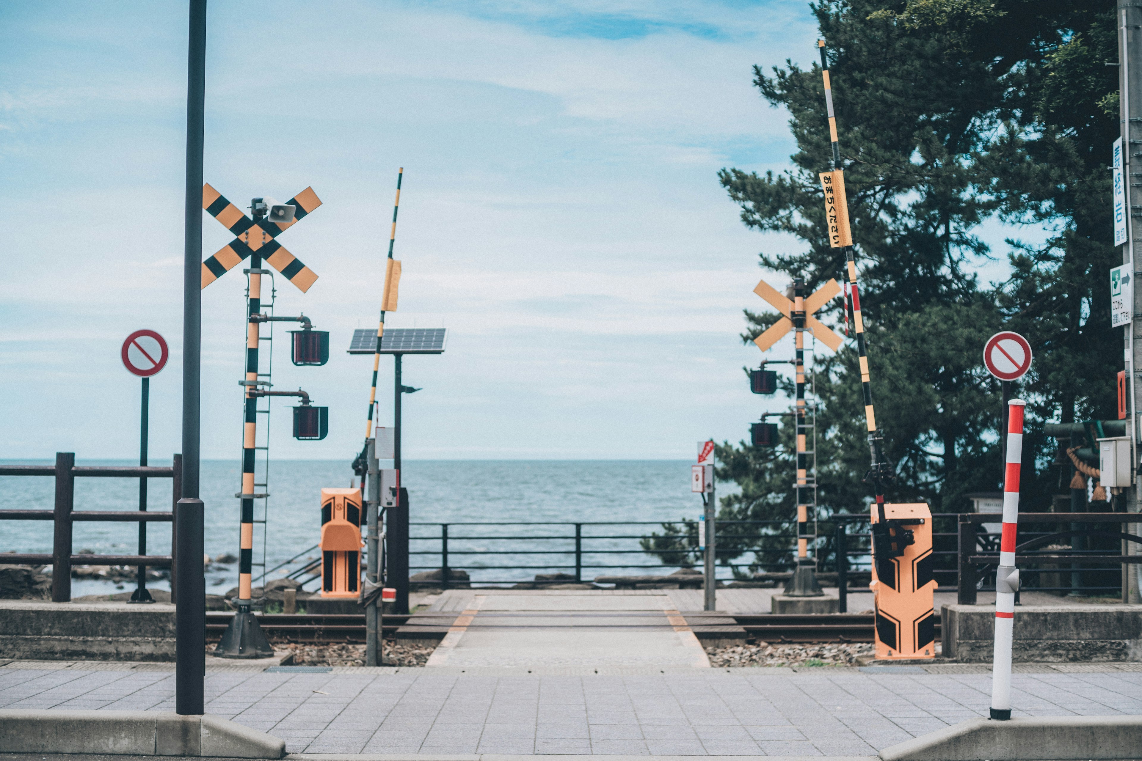 海の近くの鉄道踏切と青い空