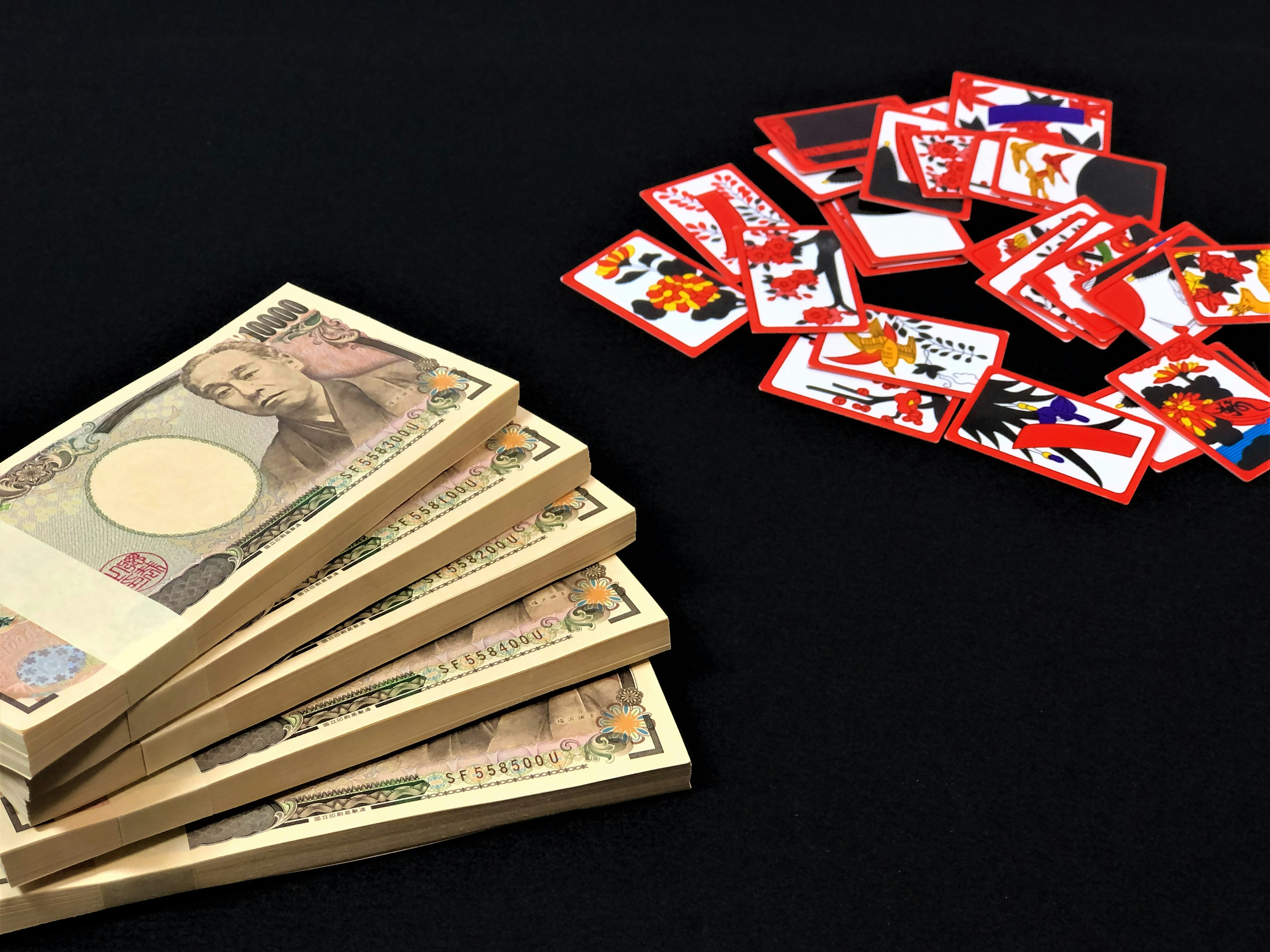 Stack of Japanese yen bills next to colorful cards on a black background