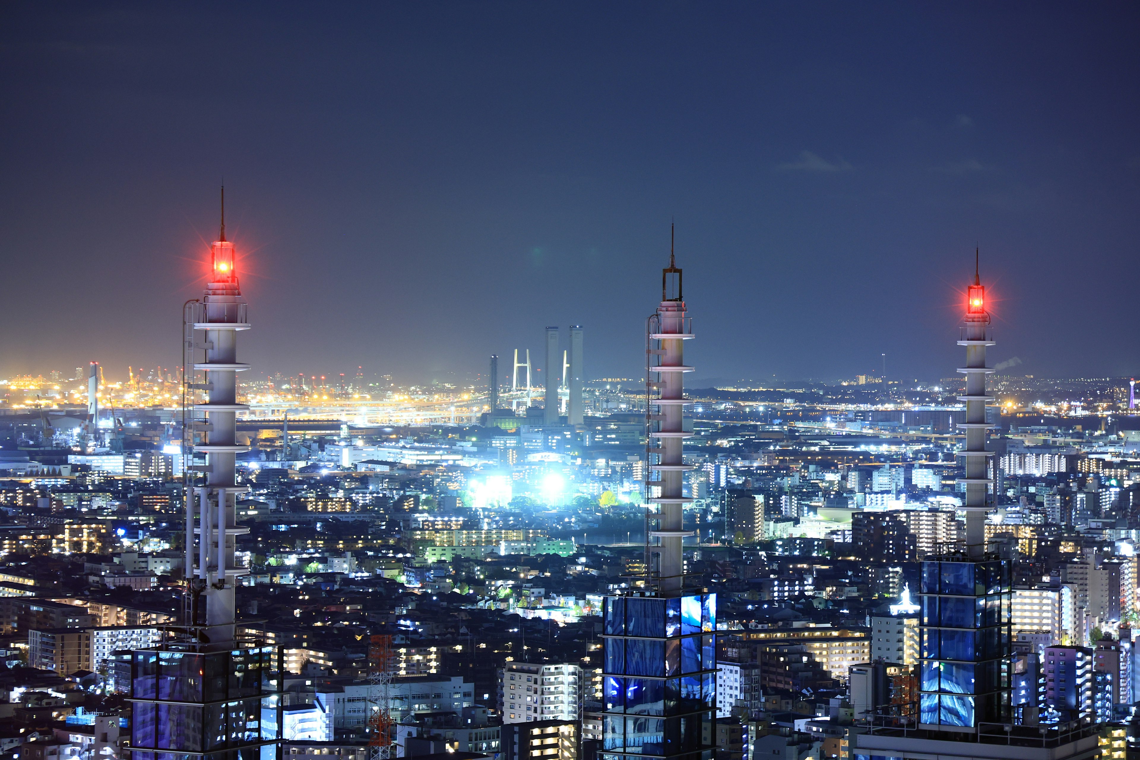 Tokyo skyline at night featuring skyscrapers and red-lit communication towers