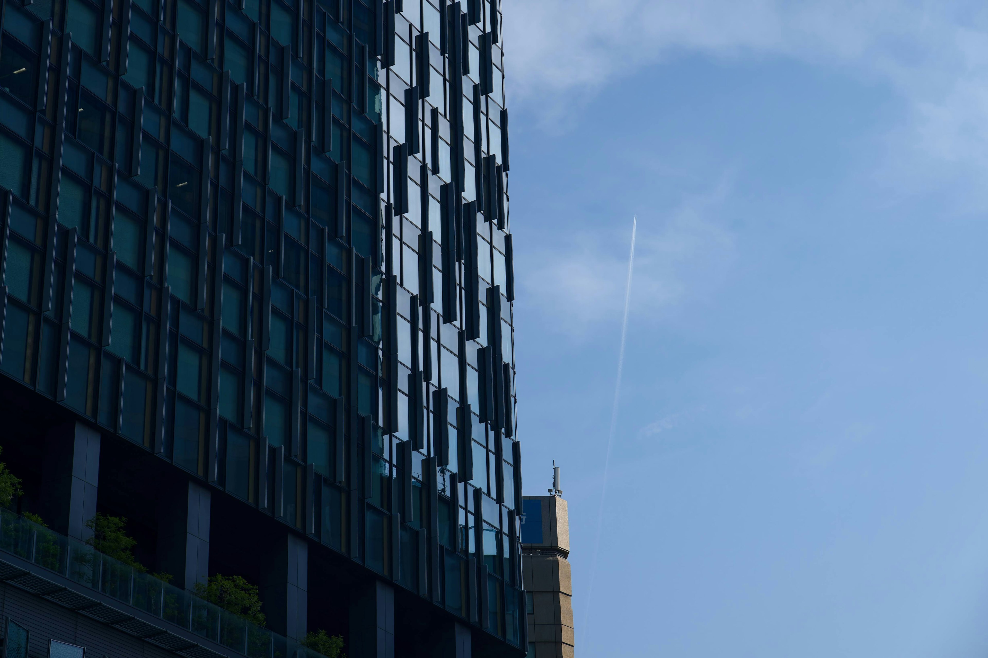 Parte de un edificio moderno que refleja vidrio bajo un cielo azul