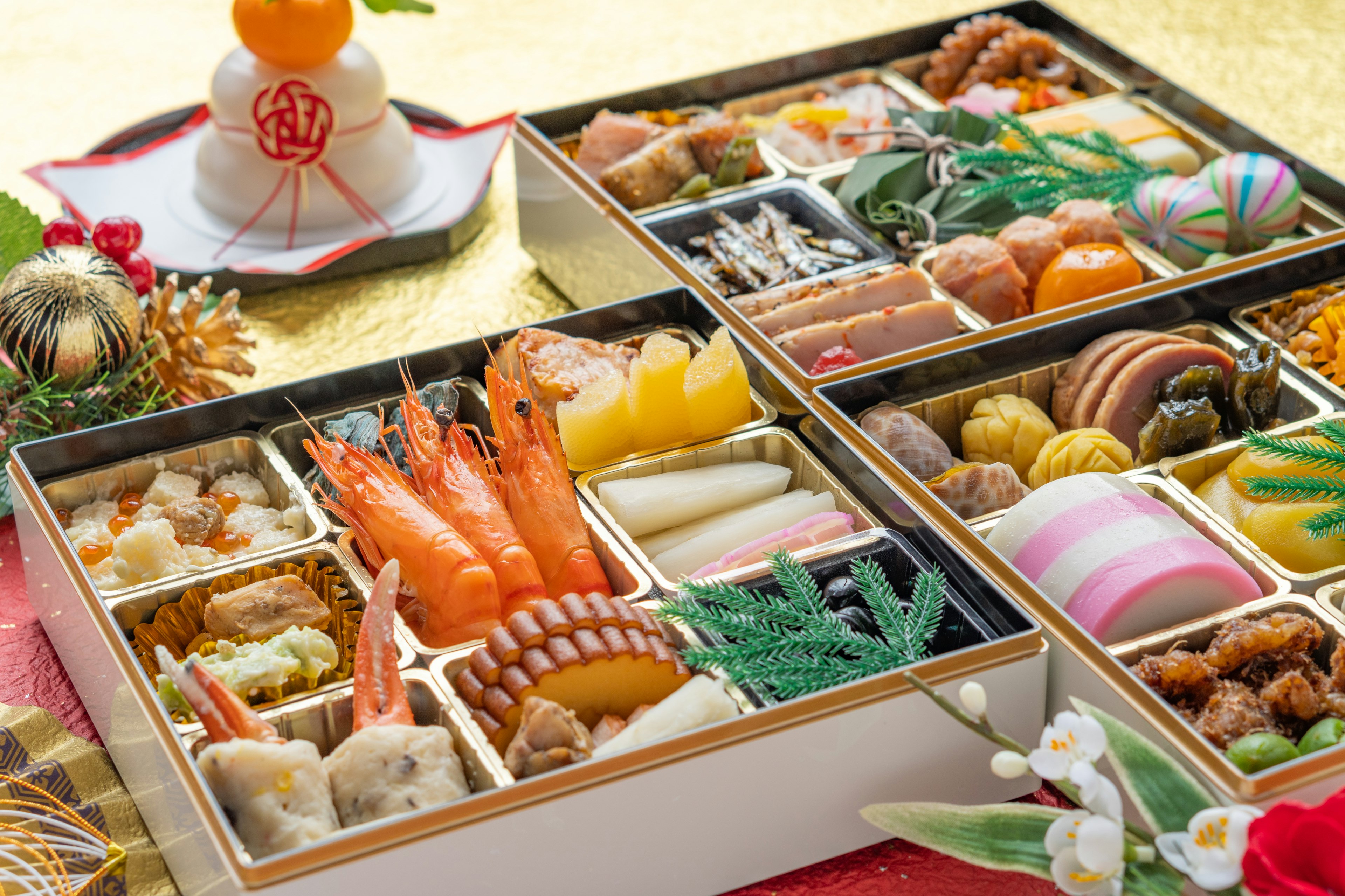 Osechi ryori splendidamente disposto in una scatola bento quadrata con daidai decorativo