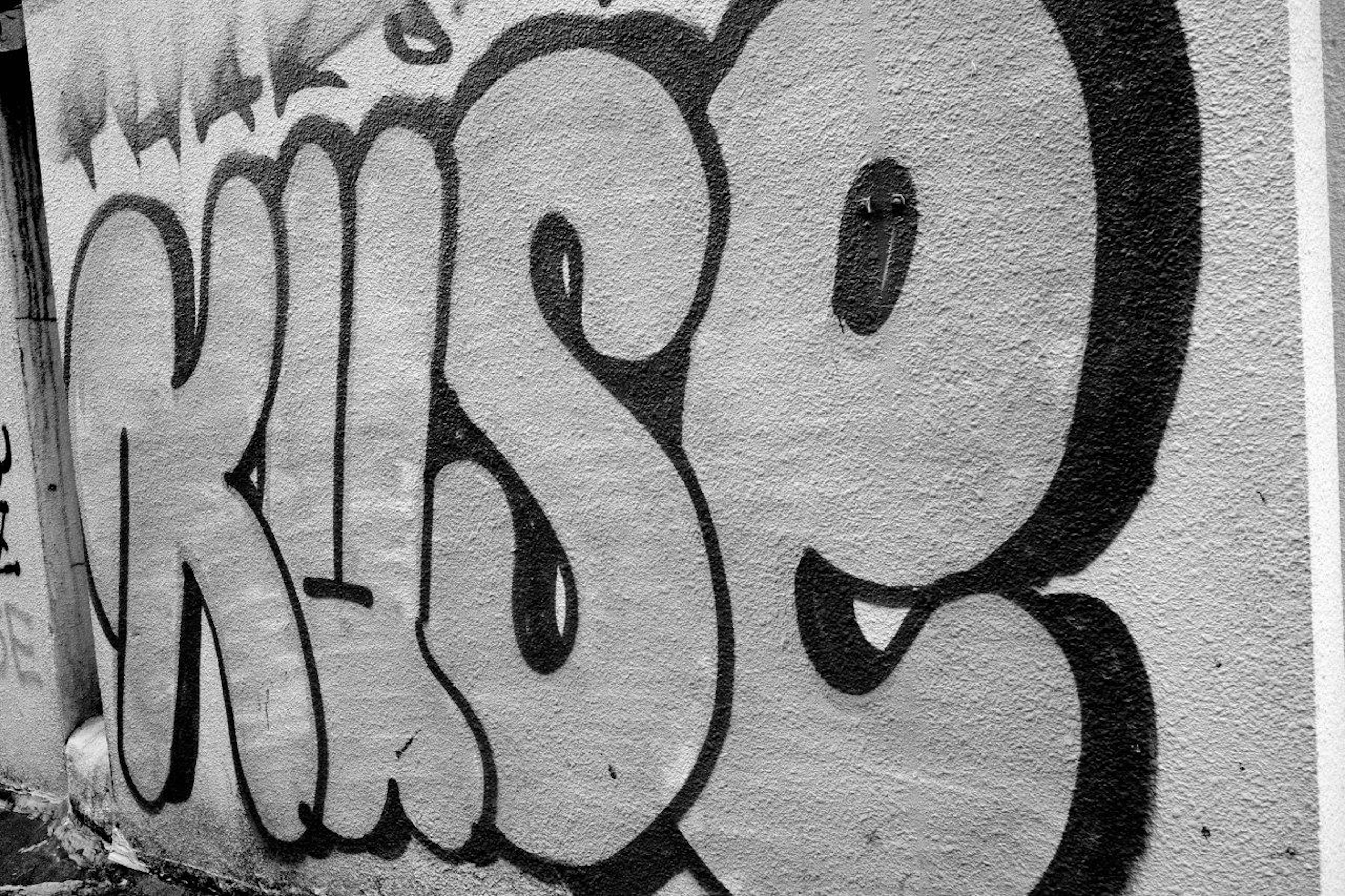 Black and white graffiti on a wall featuring the word KUSE