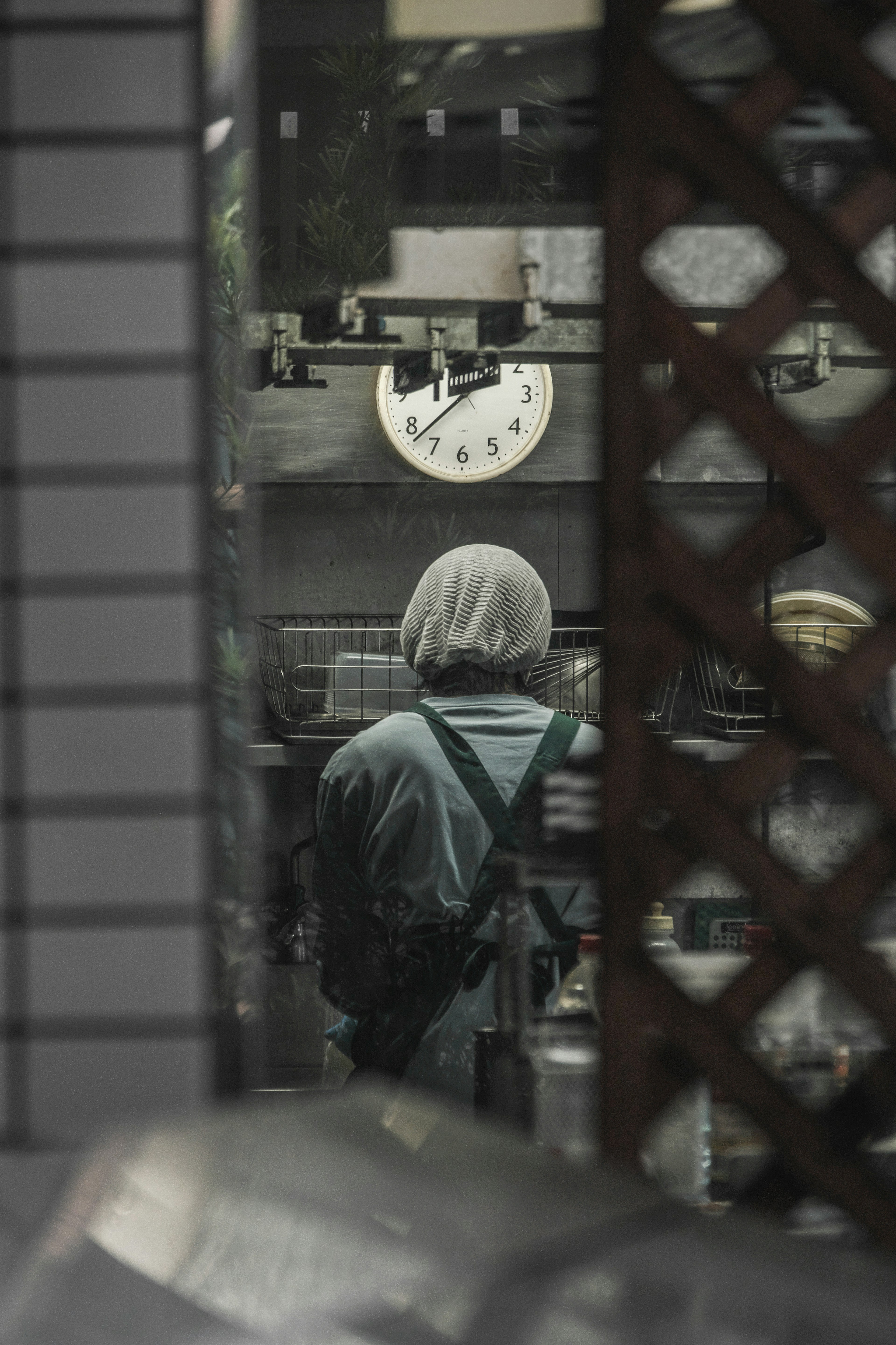 Person von hinten in einem Arbeitsraum mit einer Uhr