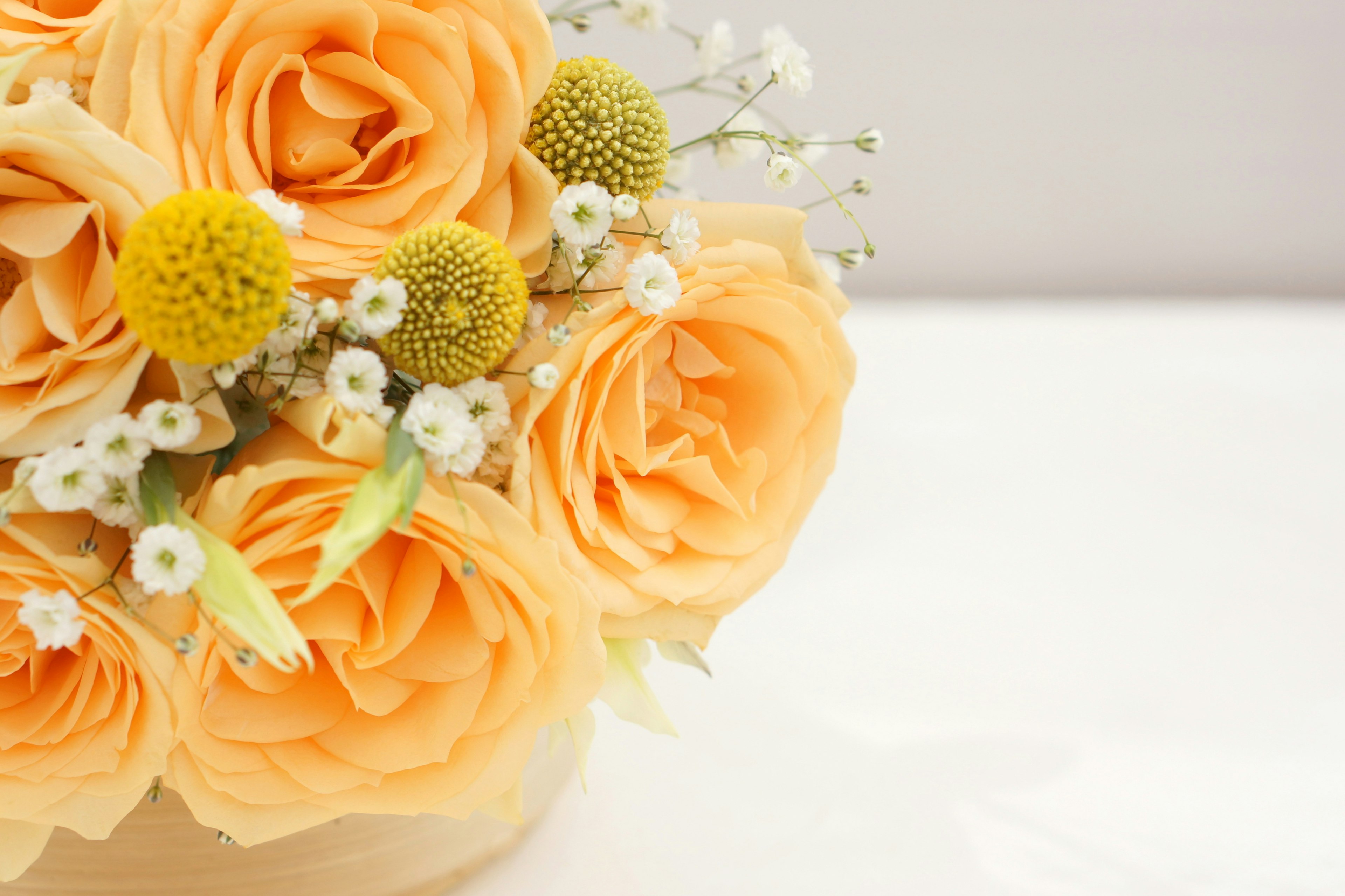 Strauß aus orangefarbenen Rosen mit weißen Blumen und gelben Akzenten