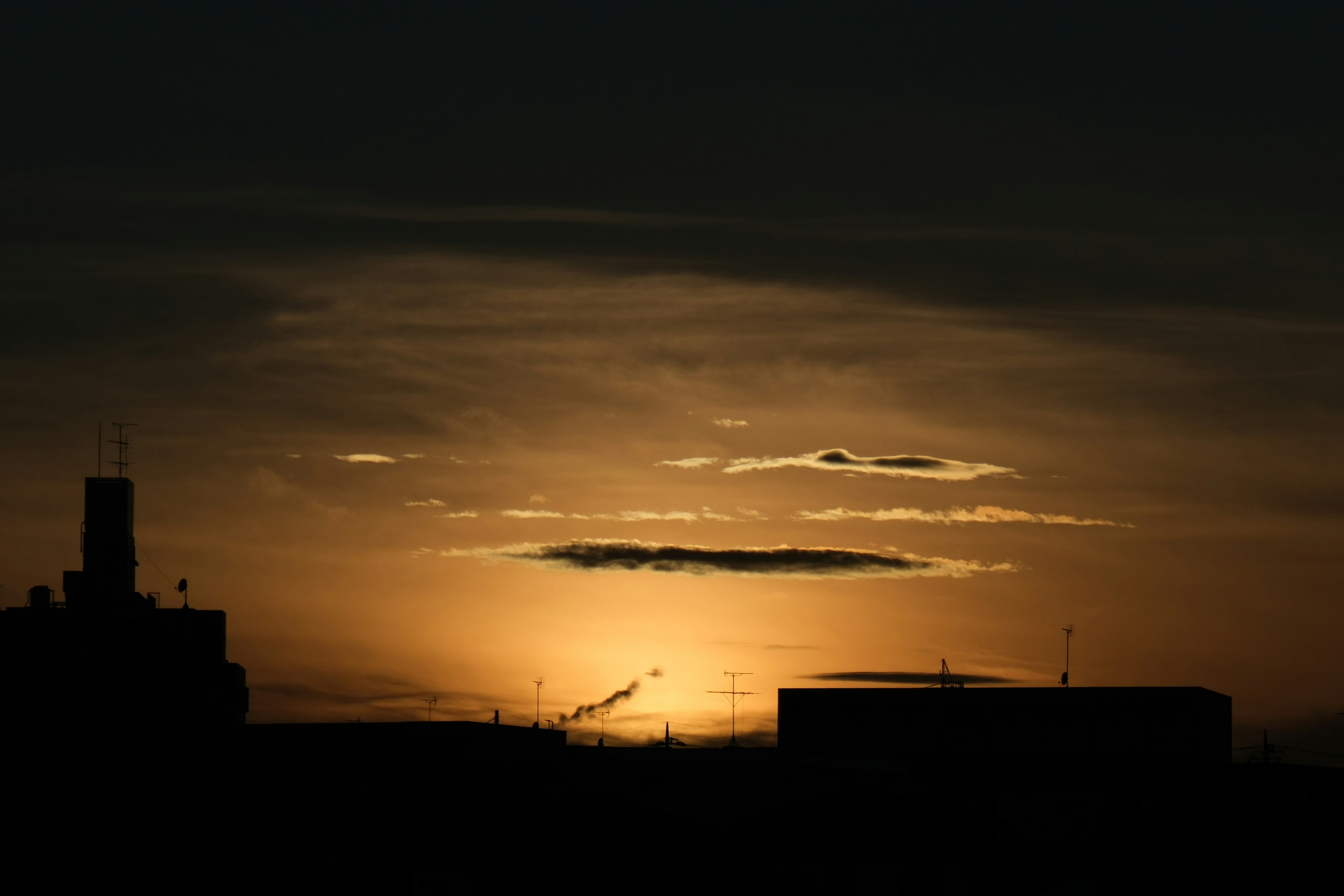 Silhouette einer Stadt bei Sonnenuntergang mit Wolken in einem dunklen Himmel