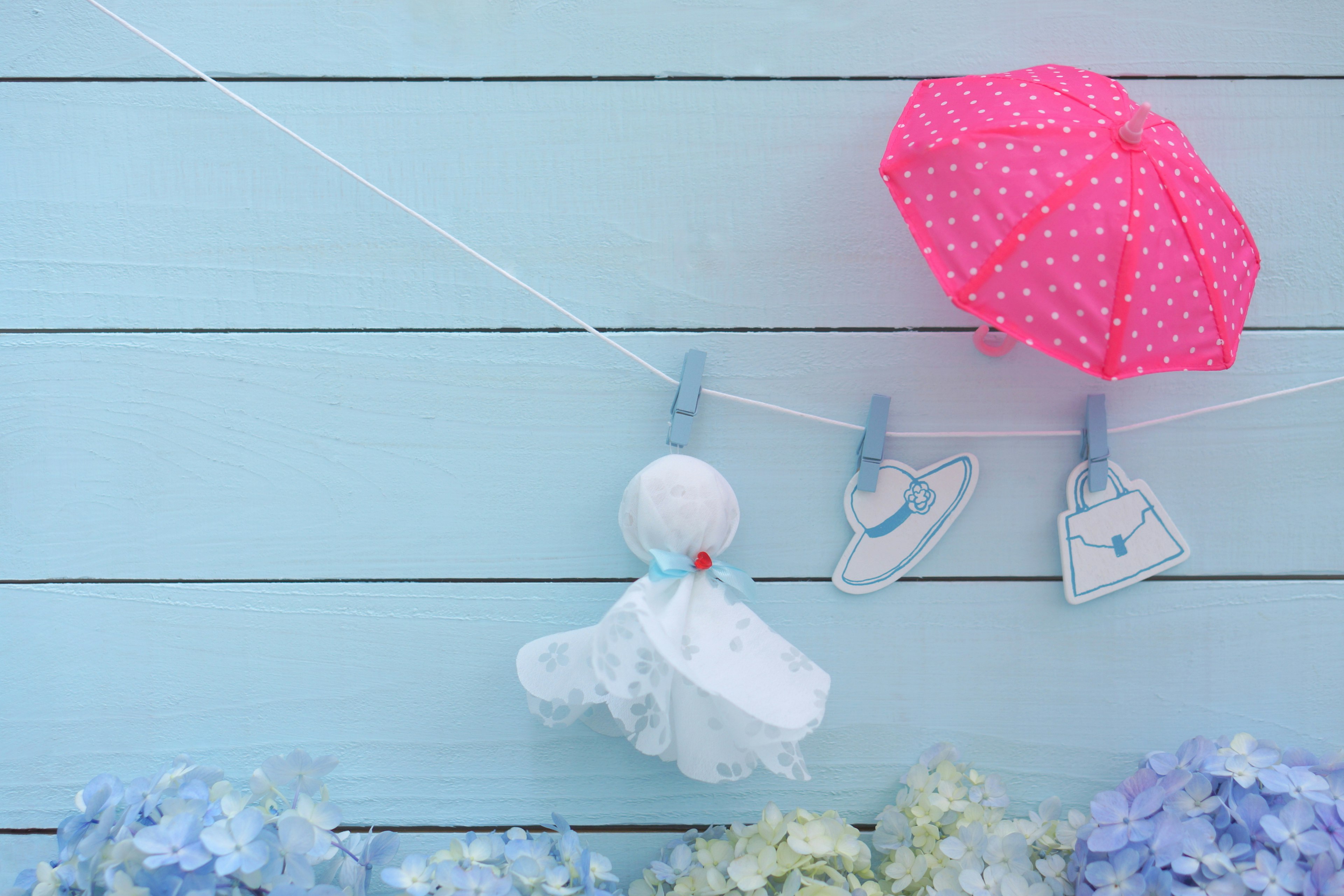 Display of a pink polka dot umbrella and white clothing hanging on a blue wall