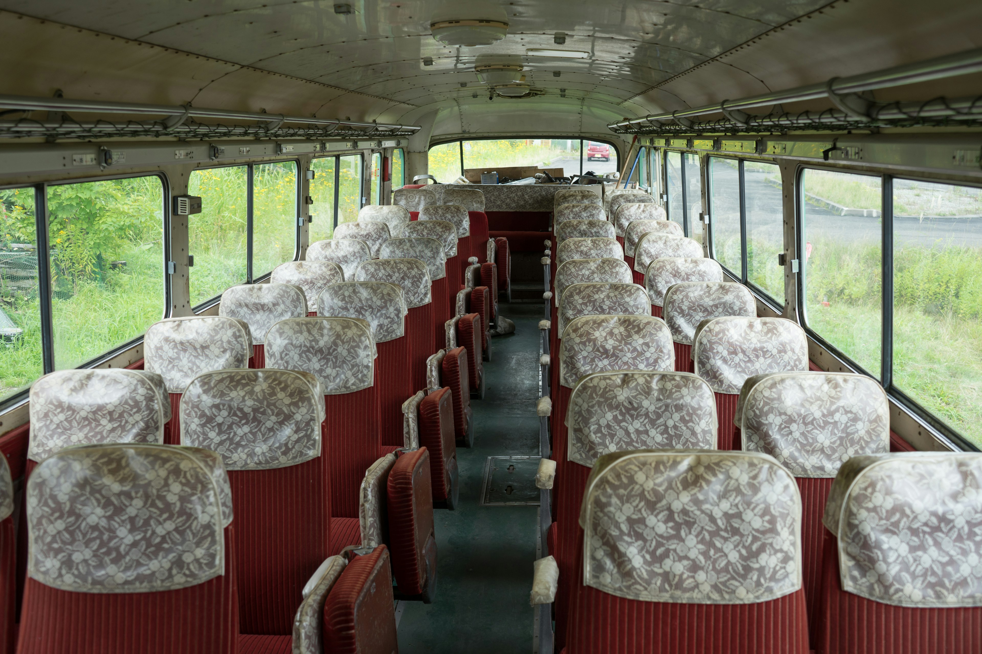 Innenraum eines Busses mit roten Sitzen und floralen Bezügen