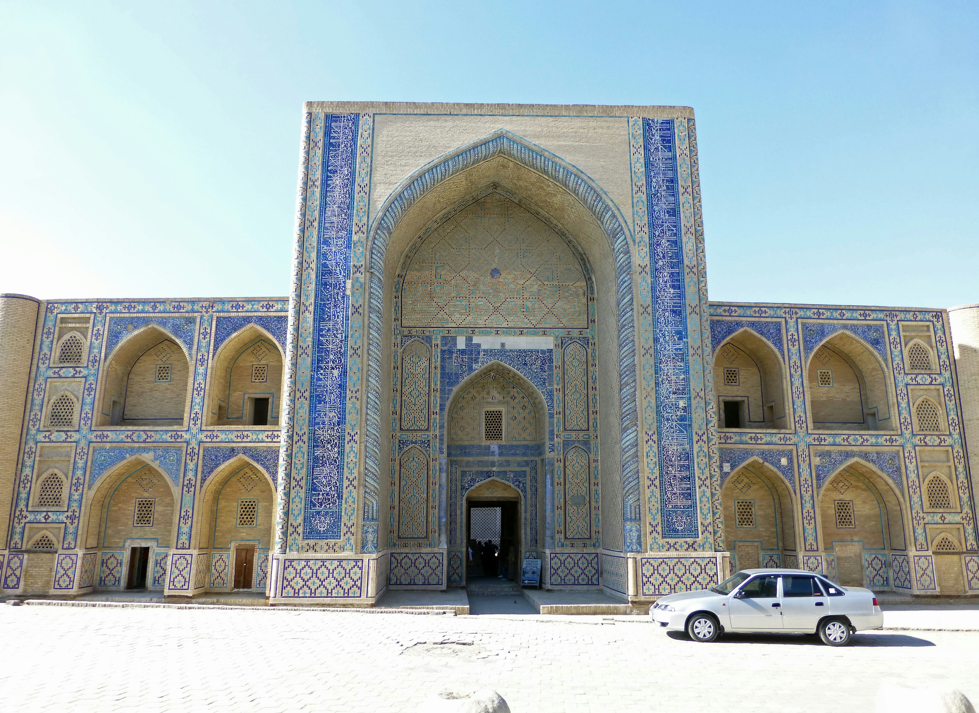 Grande entrée d'un bâtiment ornée de carreaux bleus et arcade environnante