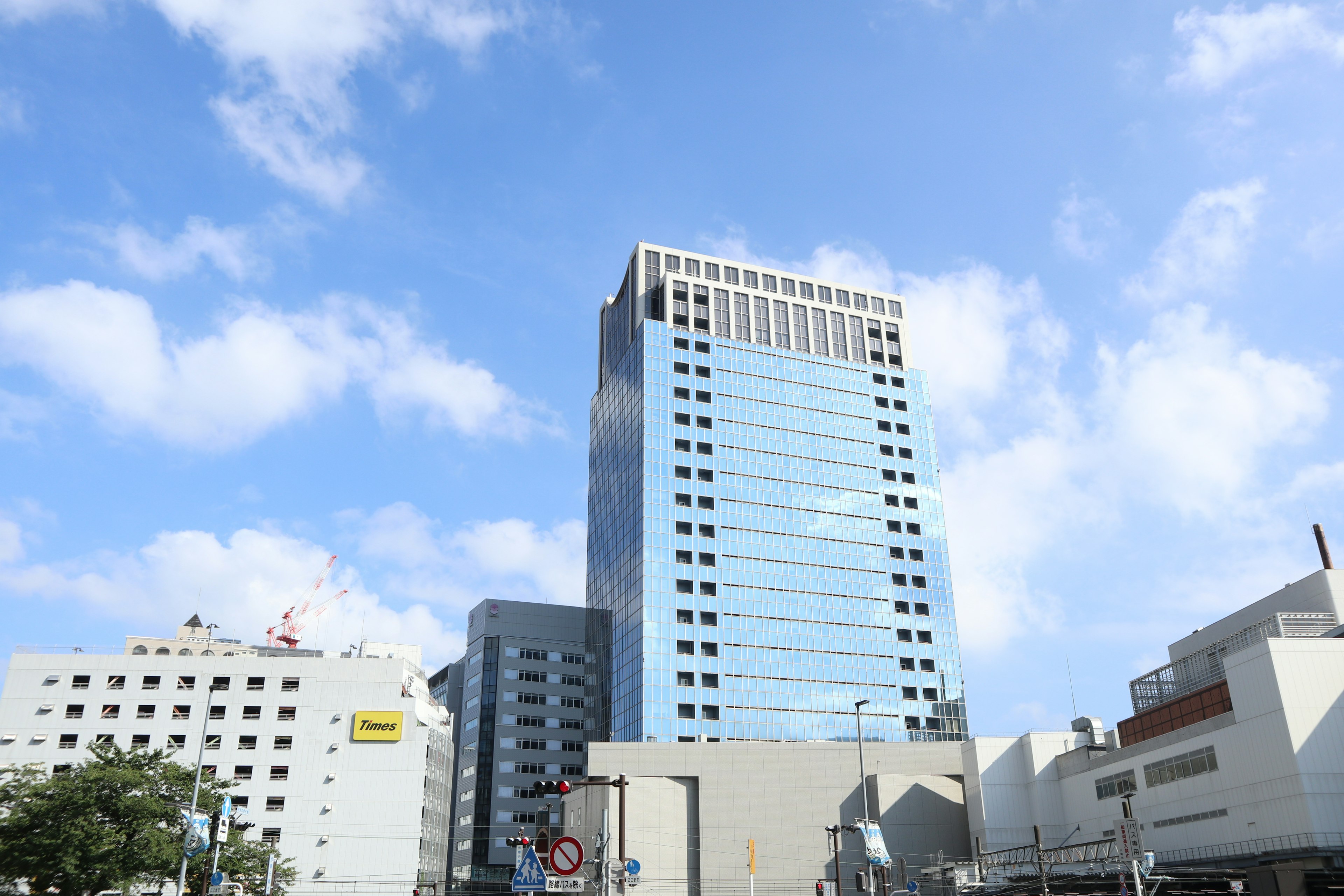 青空の下に立つ近代的なビルと周囲の建物