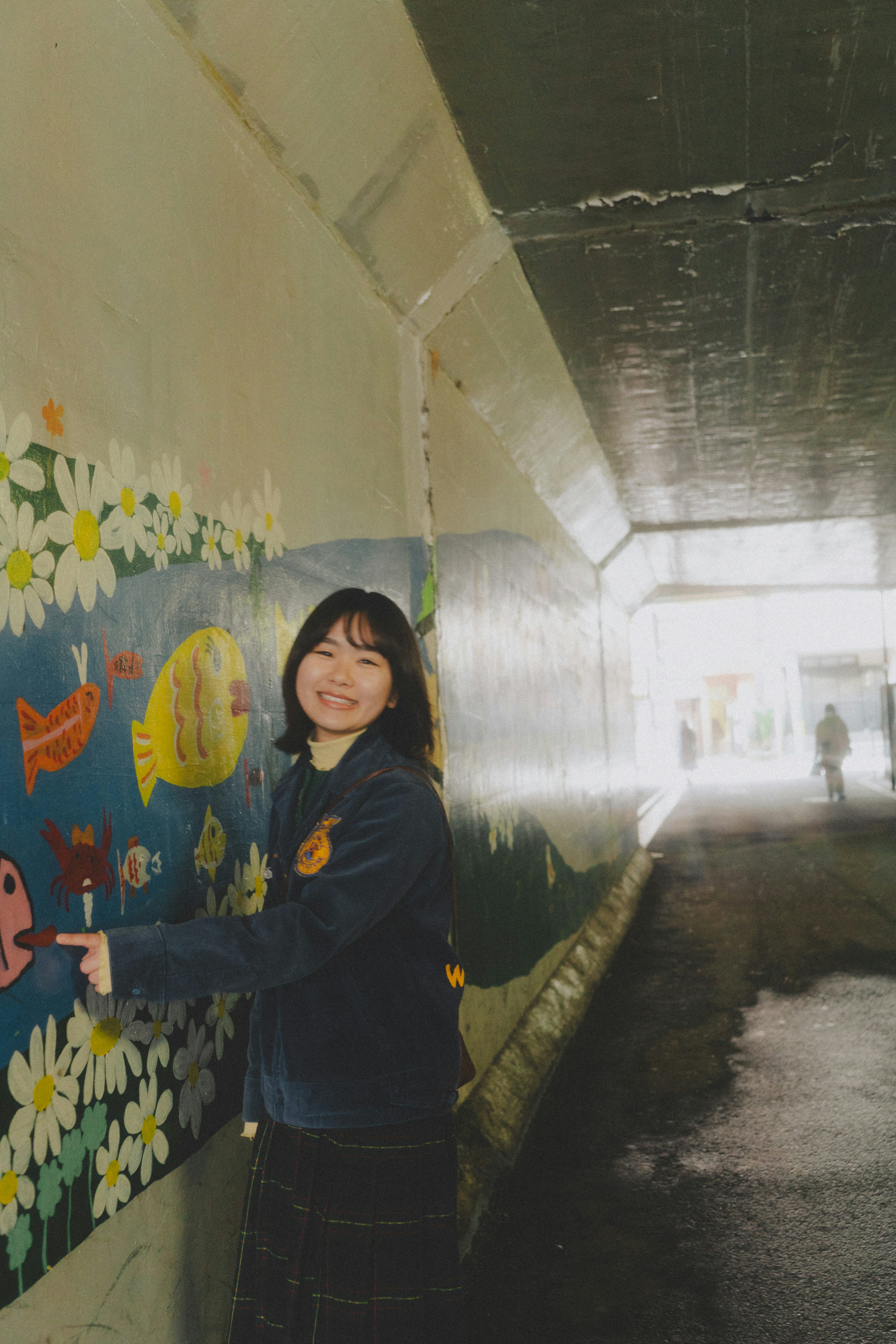 Retrato de una mujer señalando un mural en un túnel