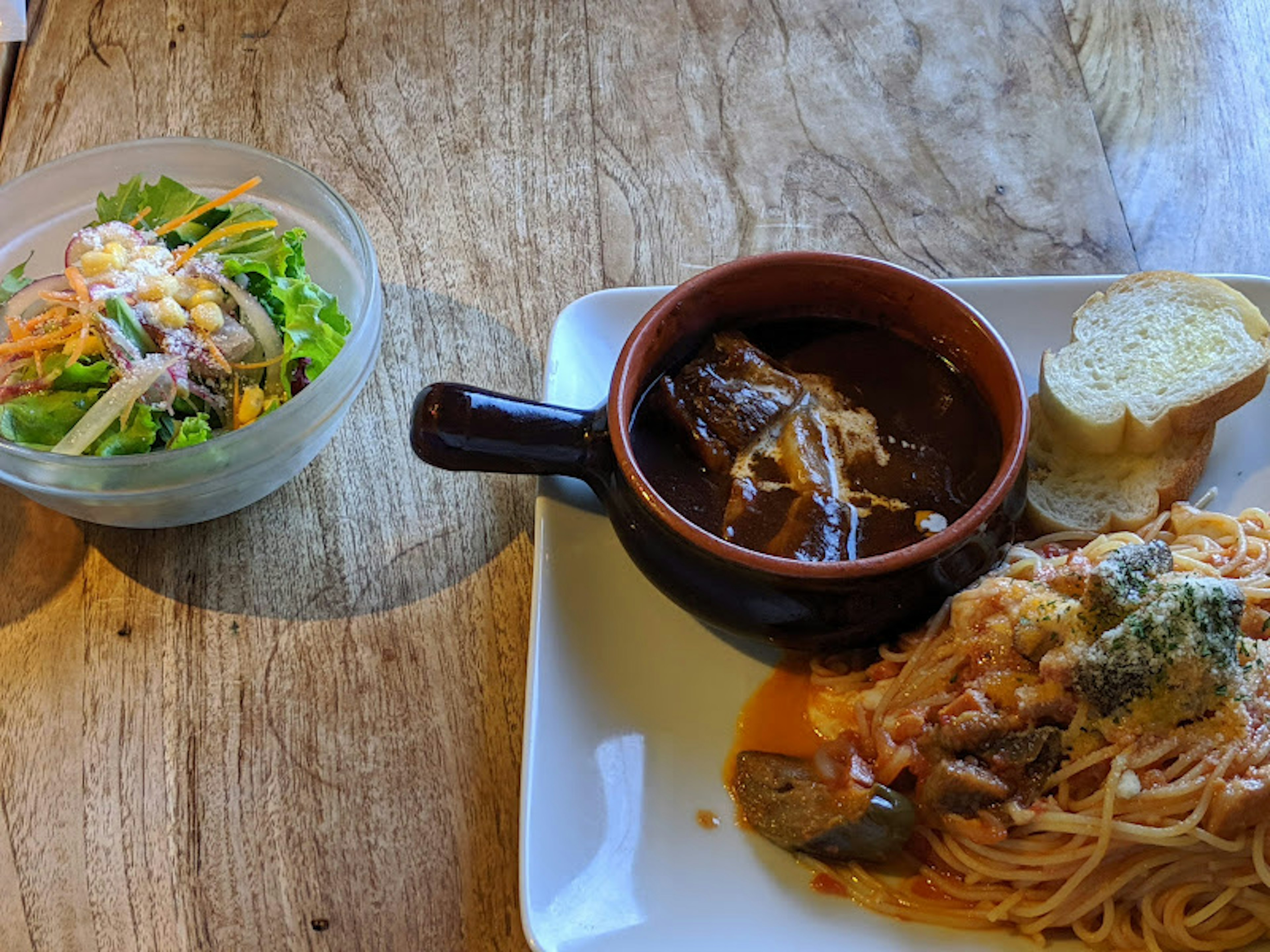 Assiette de pâtes avec salade et bol de soupe sur une table en bois