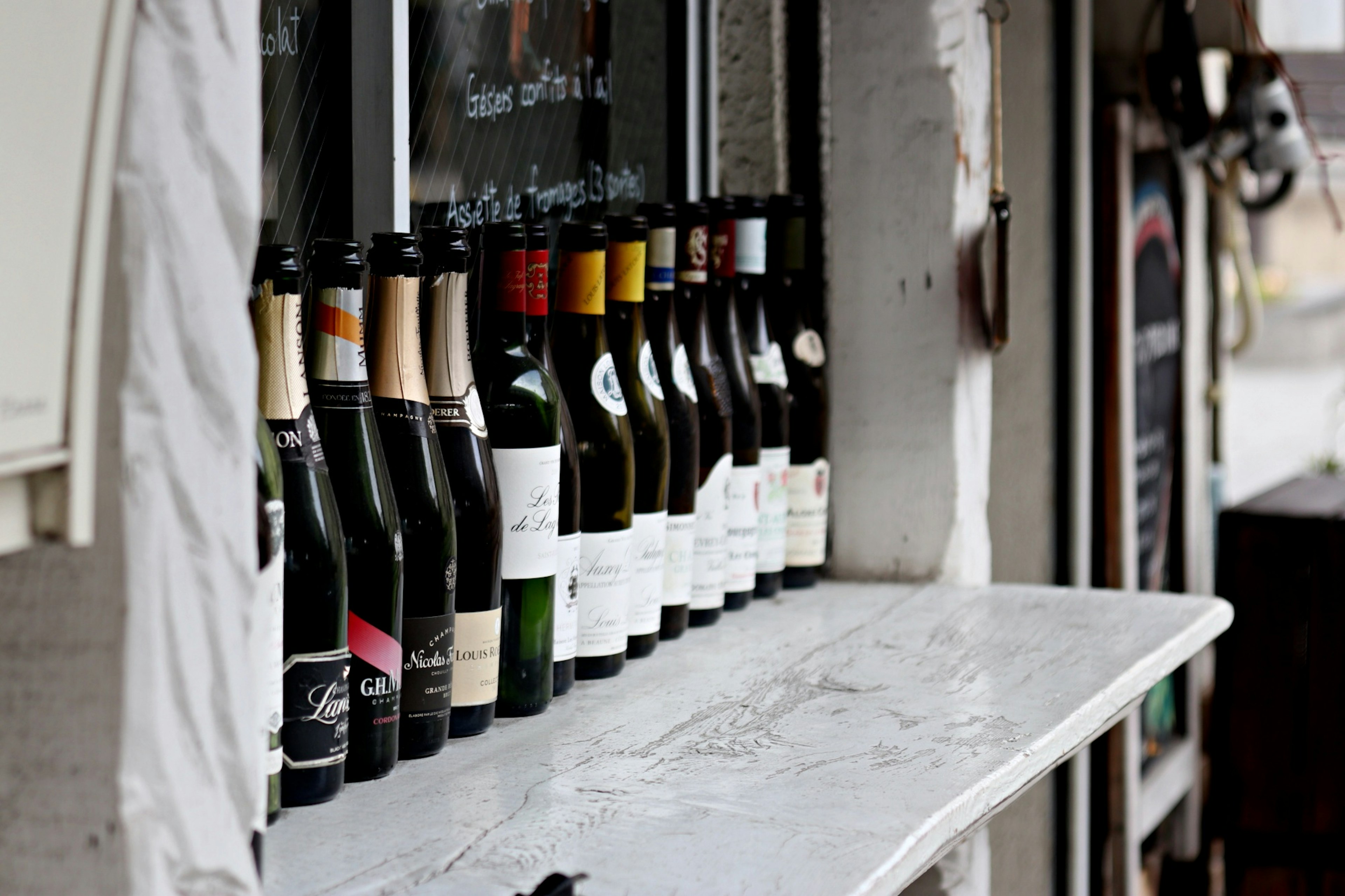 Une rangée de bouteilles de vin diverses exposées sur un rebord de fenêtre