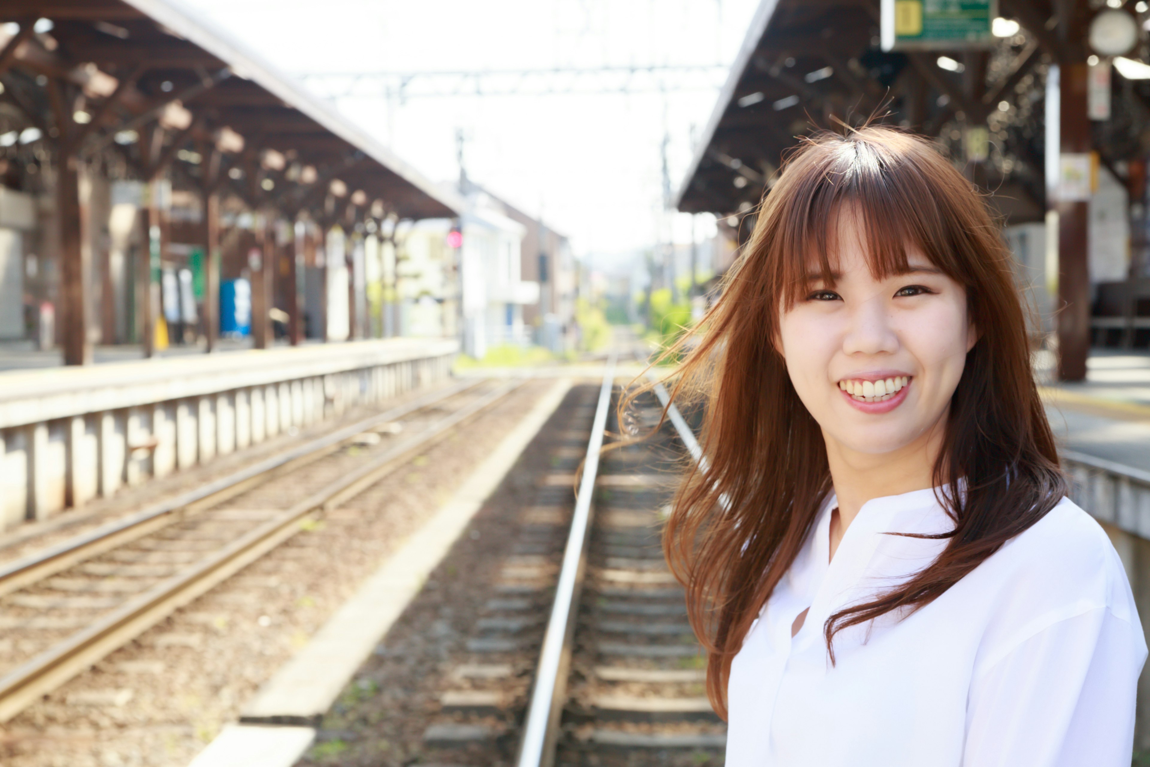 Seorang wanita tersenyum di platform stasiun kereta