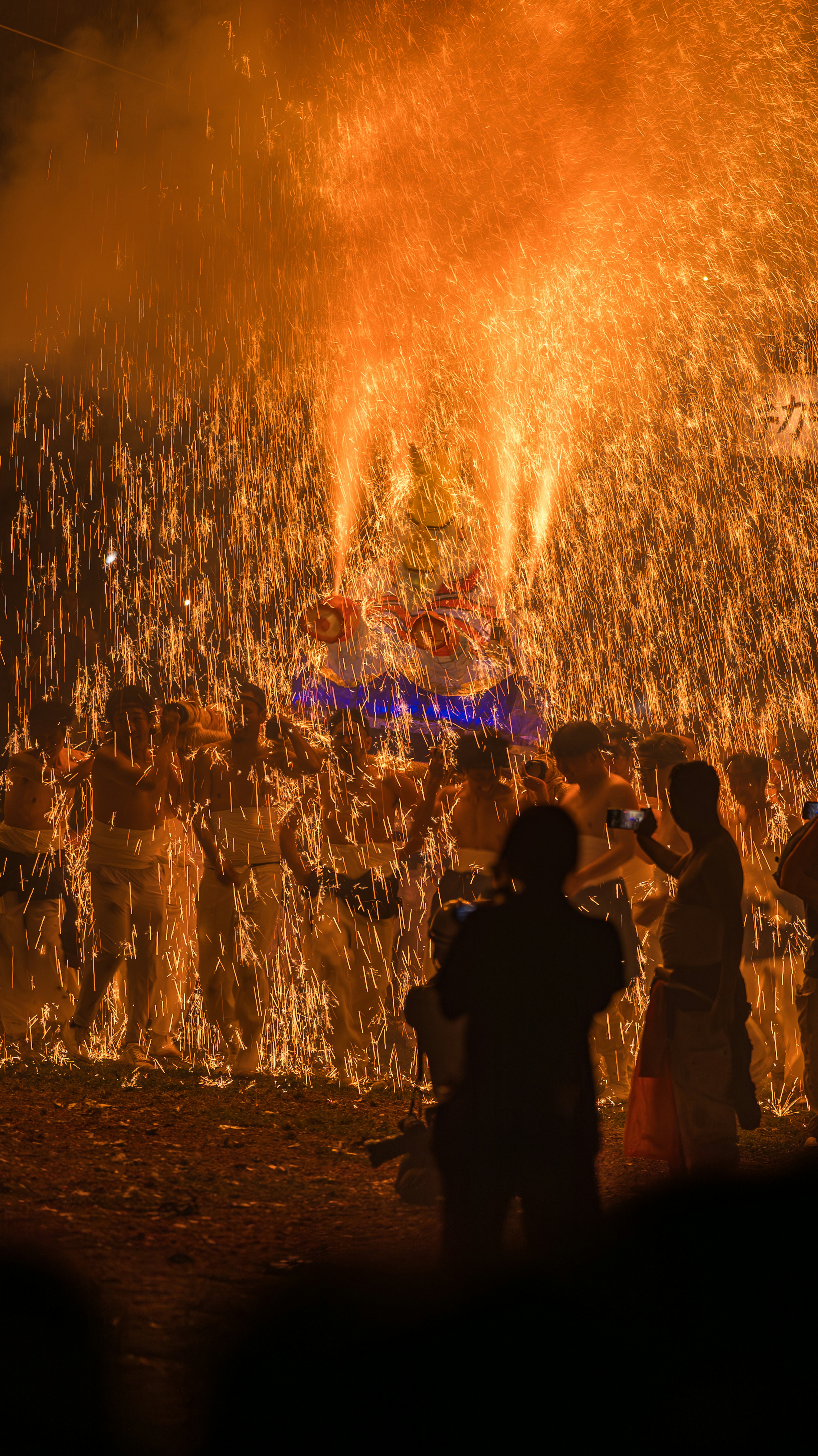 Festivalteilnehmer versammelt sich um ein großes Feuer mit Flammen und Rauch