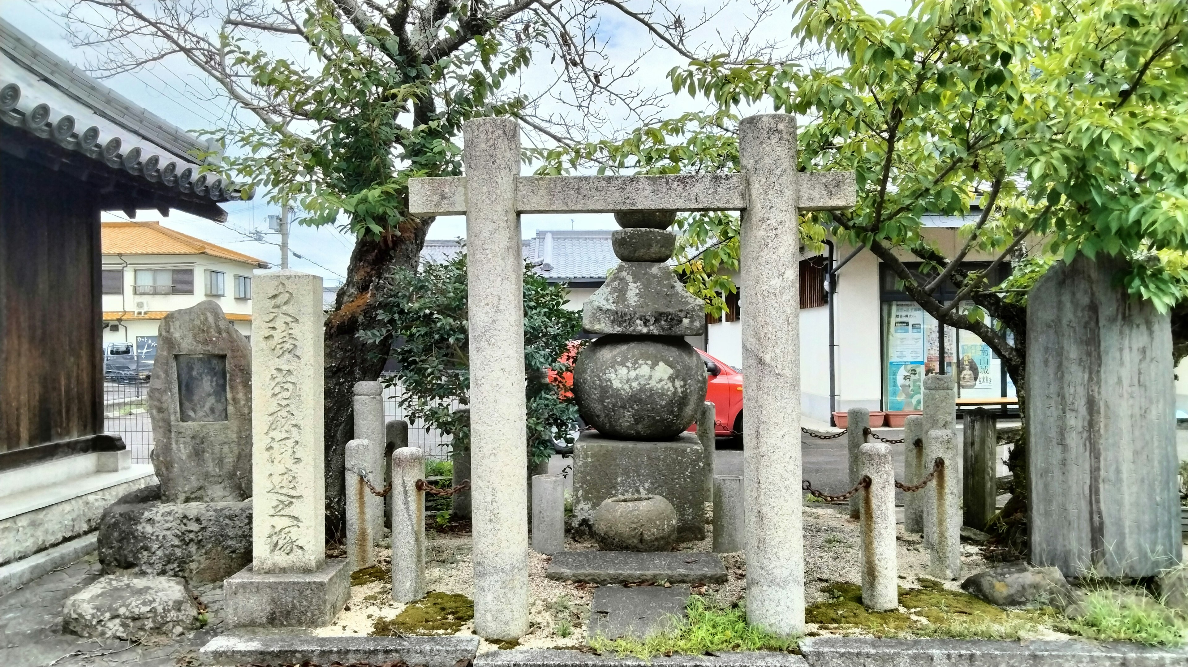 Historical site featuring stone torii gate and lantern surrounded by trees