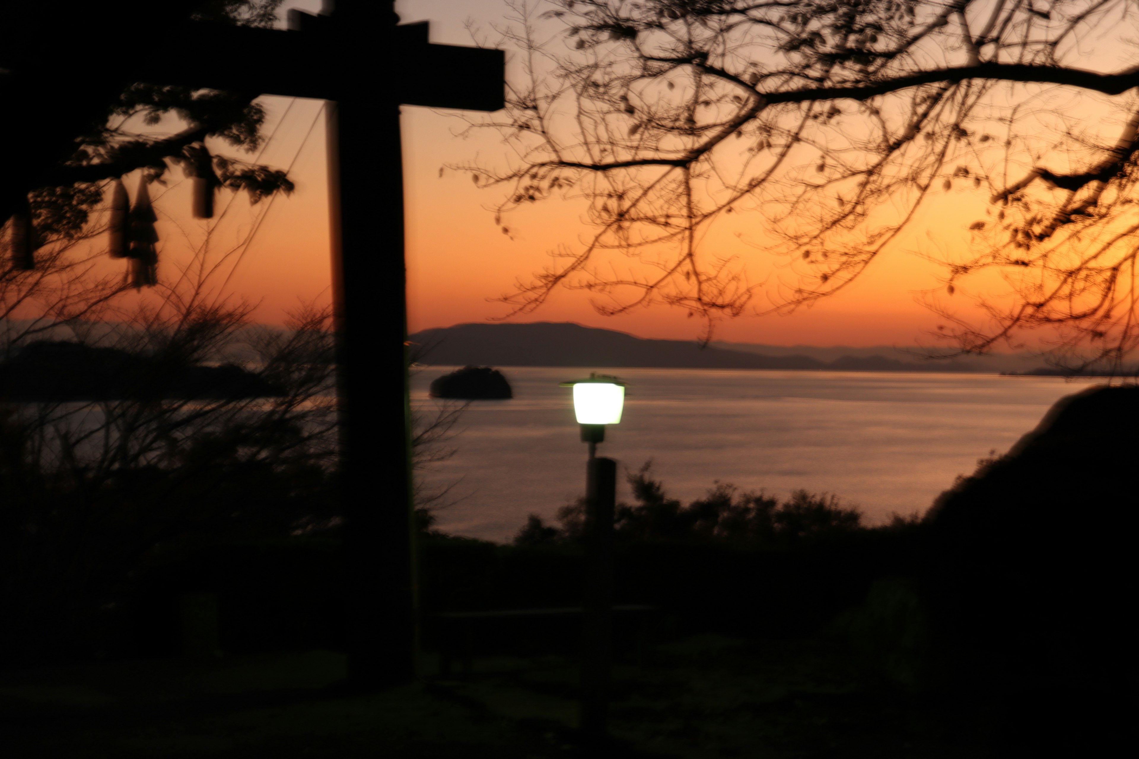 Silhouette einer Straßenlaterne gegen einen Sonnenuntergang über dem Meer