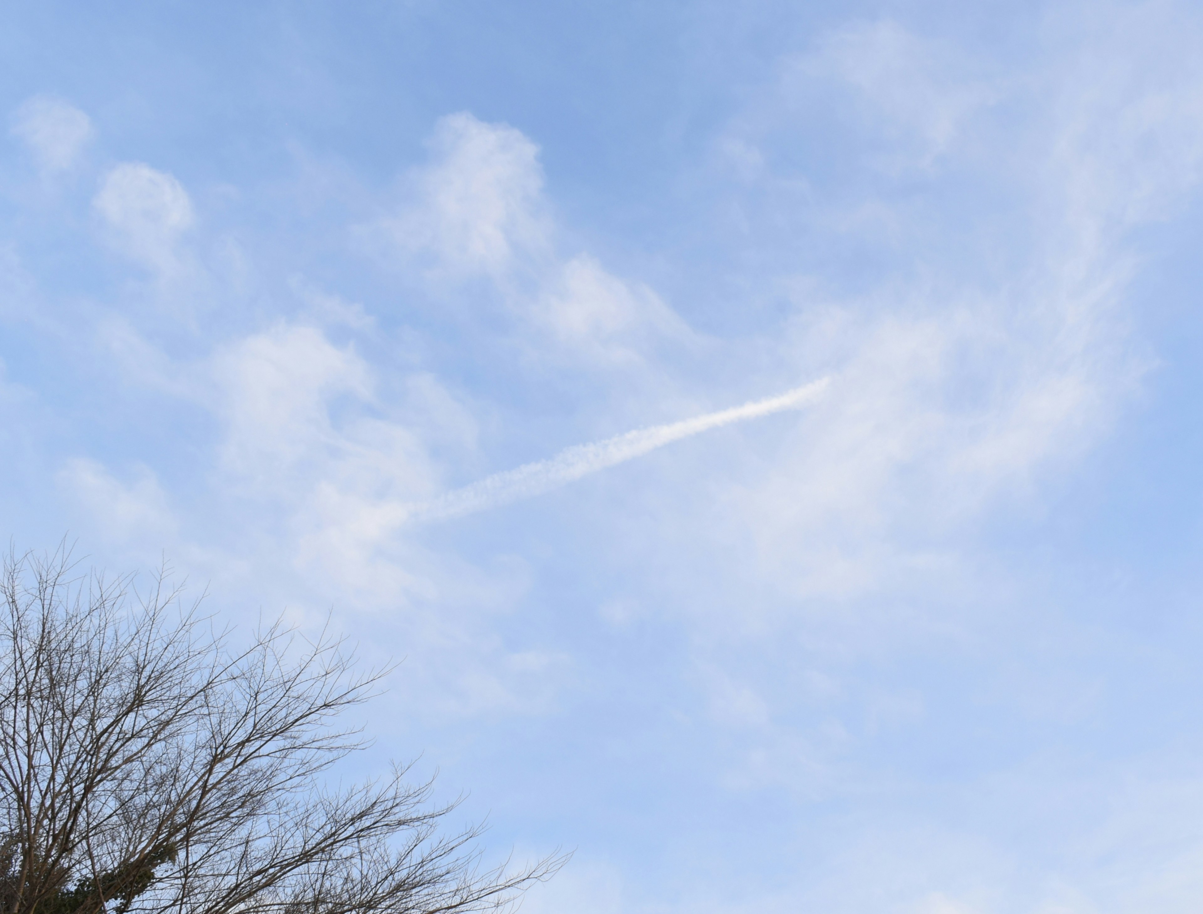 Un ciel bleu avec des nuages blancs et une traînée d'avion