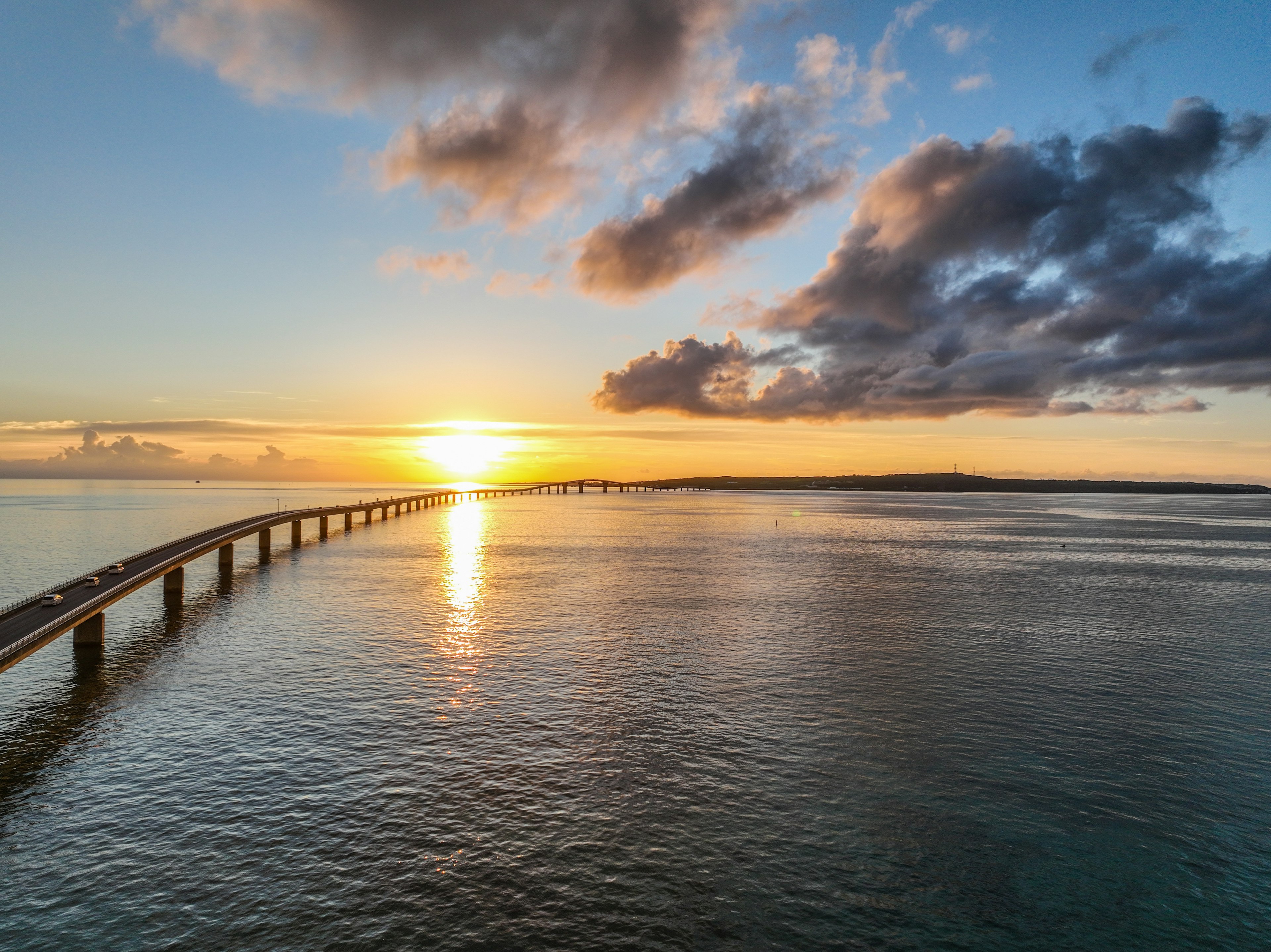 Pont s'étendant sur des eaux calmes au coucher du soleil