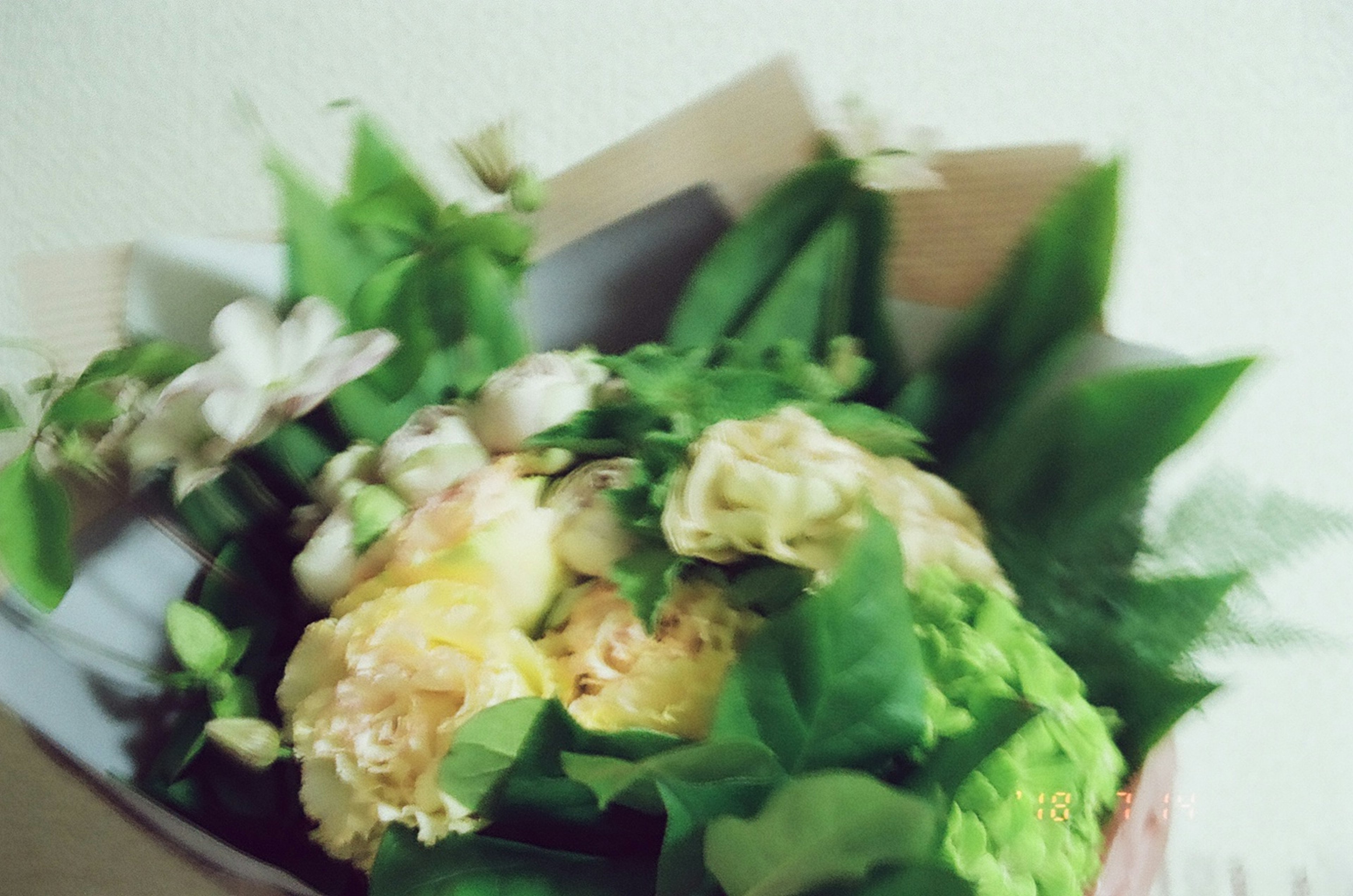 A bouquet featuring green and yellow flowers mixed with white blossoms and leaves