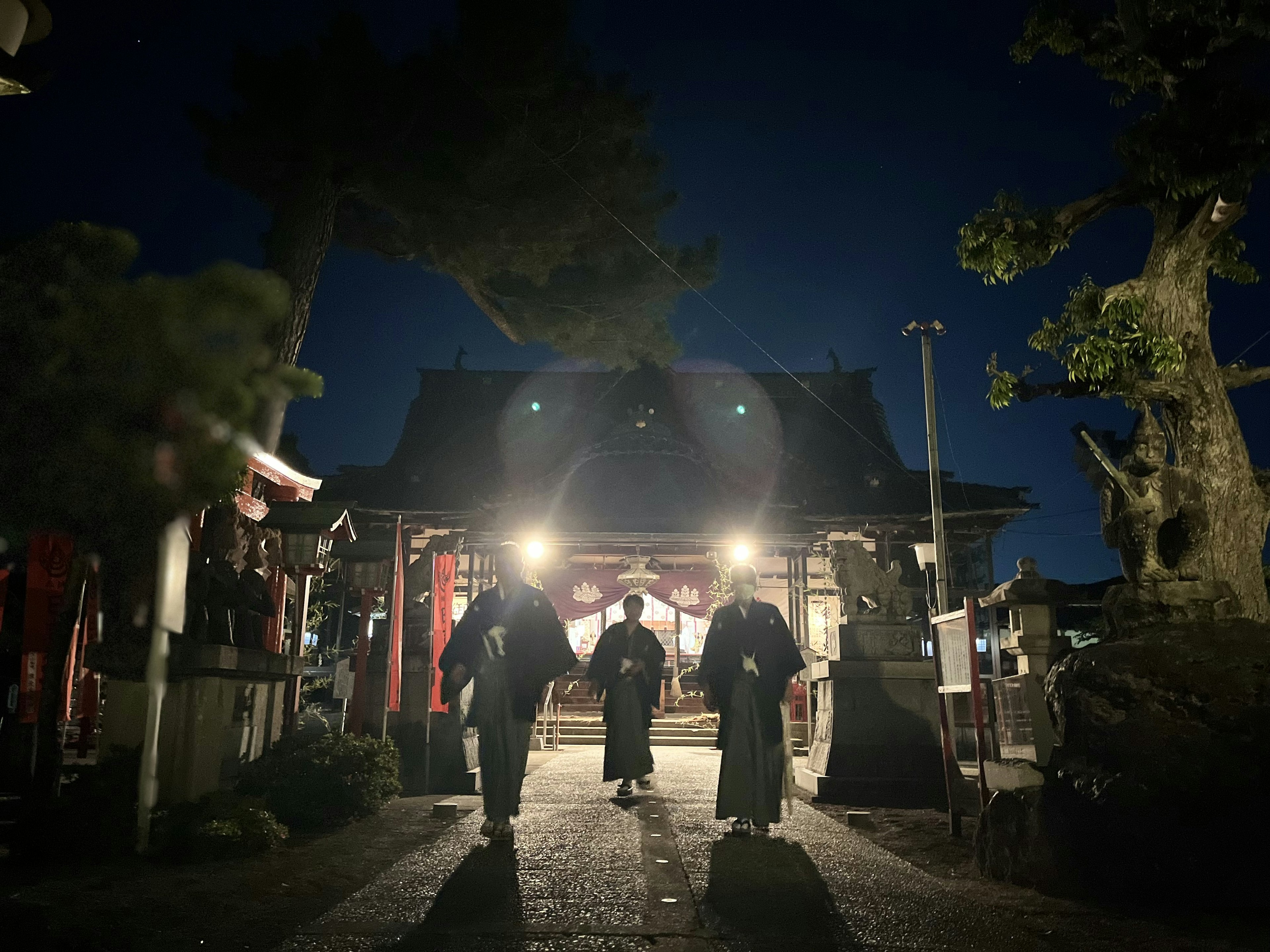 Silhouetten von Personen, die nachts in einem beleuchteten Schrein gehen