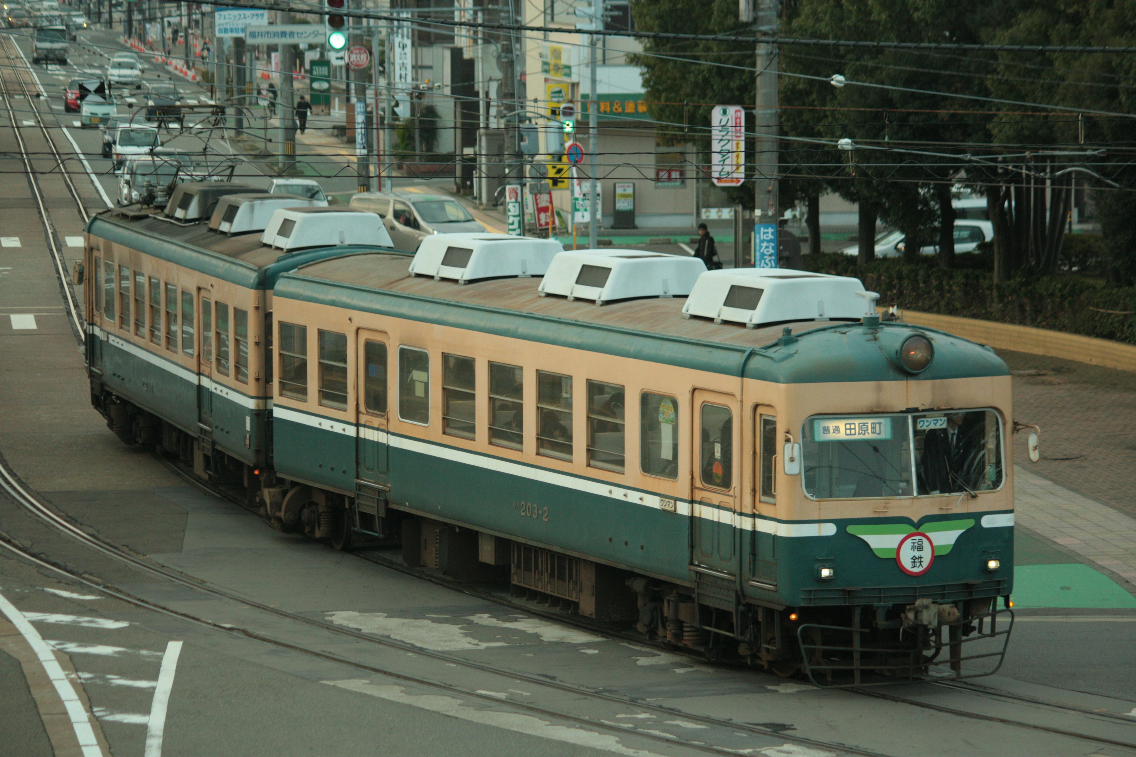 A green and orange train turning at an intersection